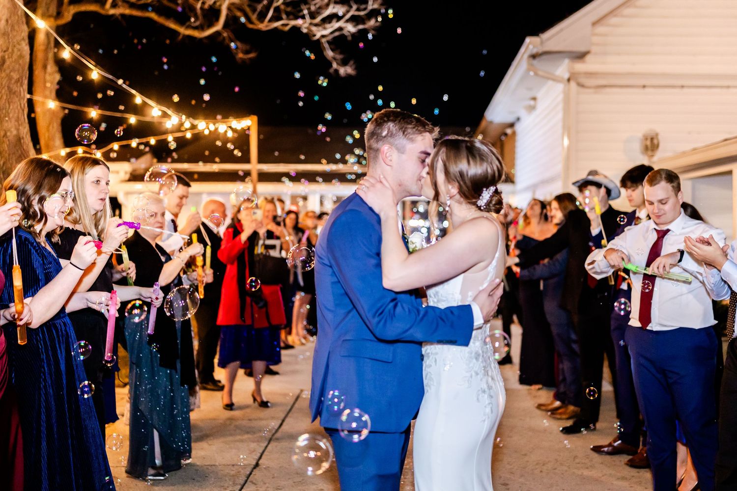 Wedding party and guests celebrate with sparklers during nighttime send-off.
