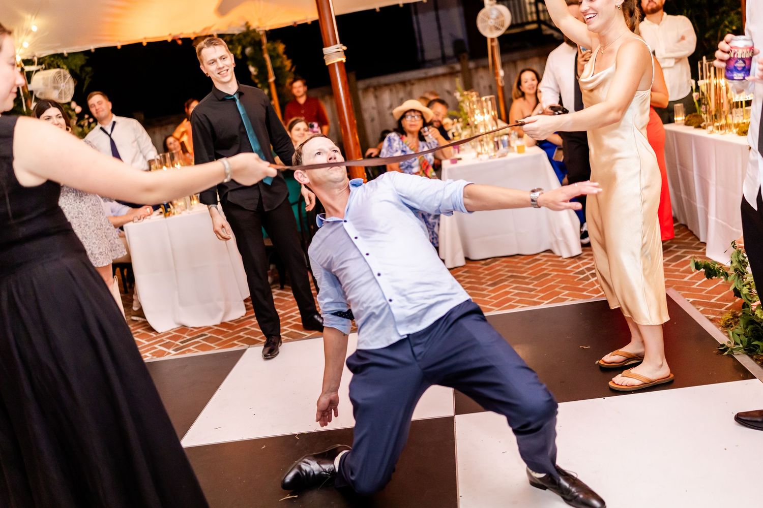 Lively dance party with guests showing off their moves on a black and white checkered floor.