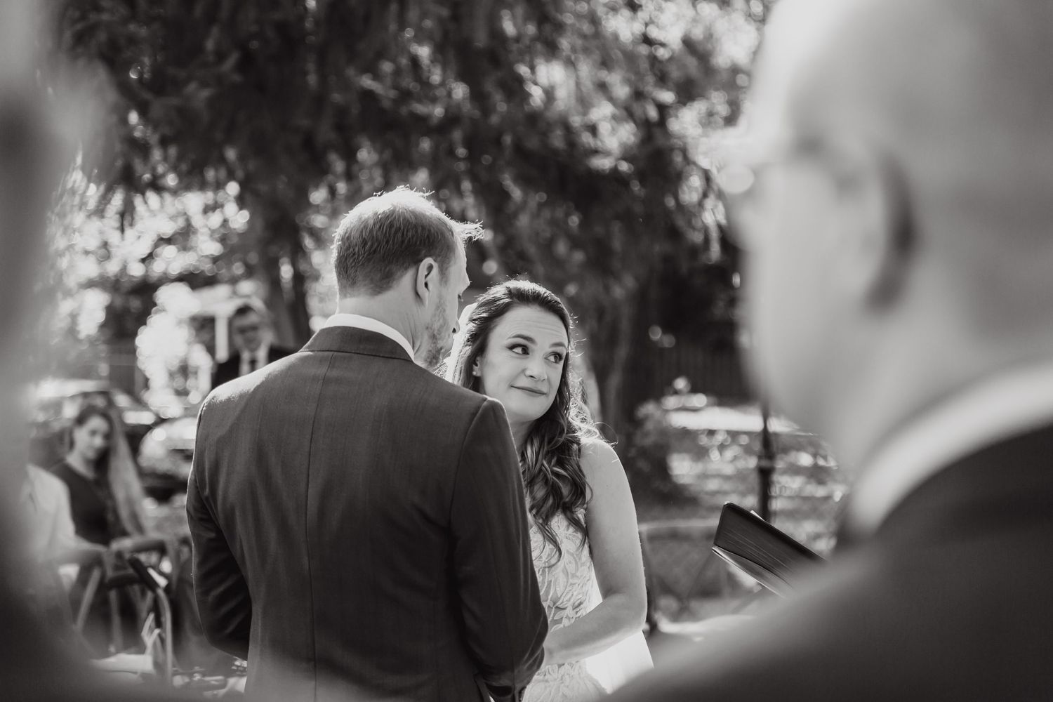 Black and white artistic shot of an intimate wedding ceremony moment outdoors.
