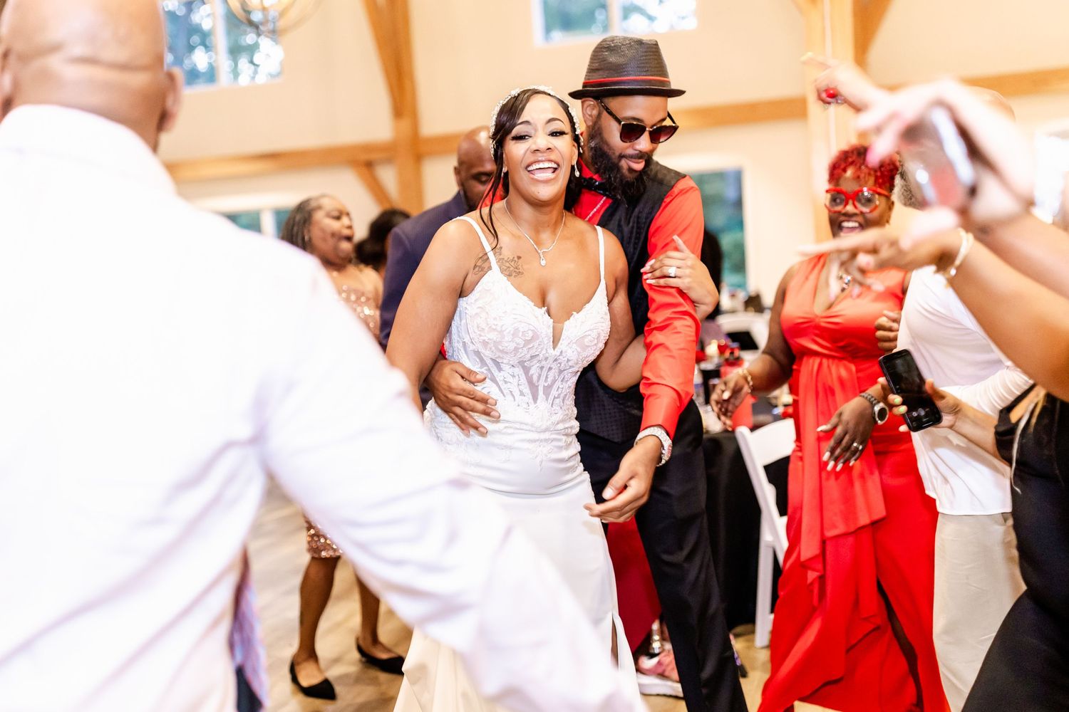 Wedding guests dancing and celebrating on the dance floor with a red accent wall in the background.