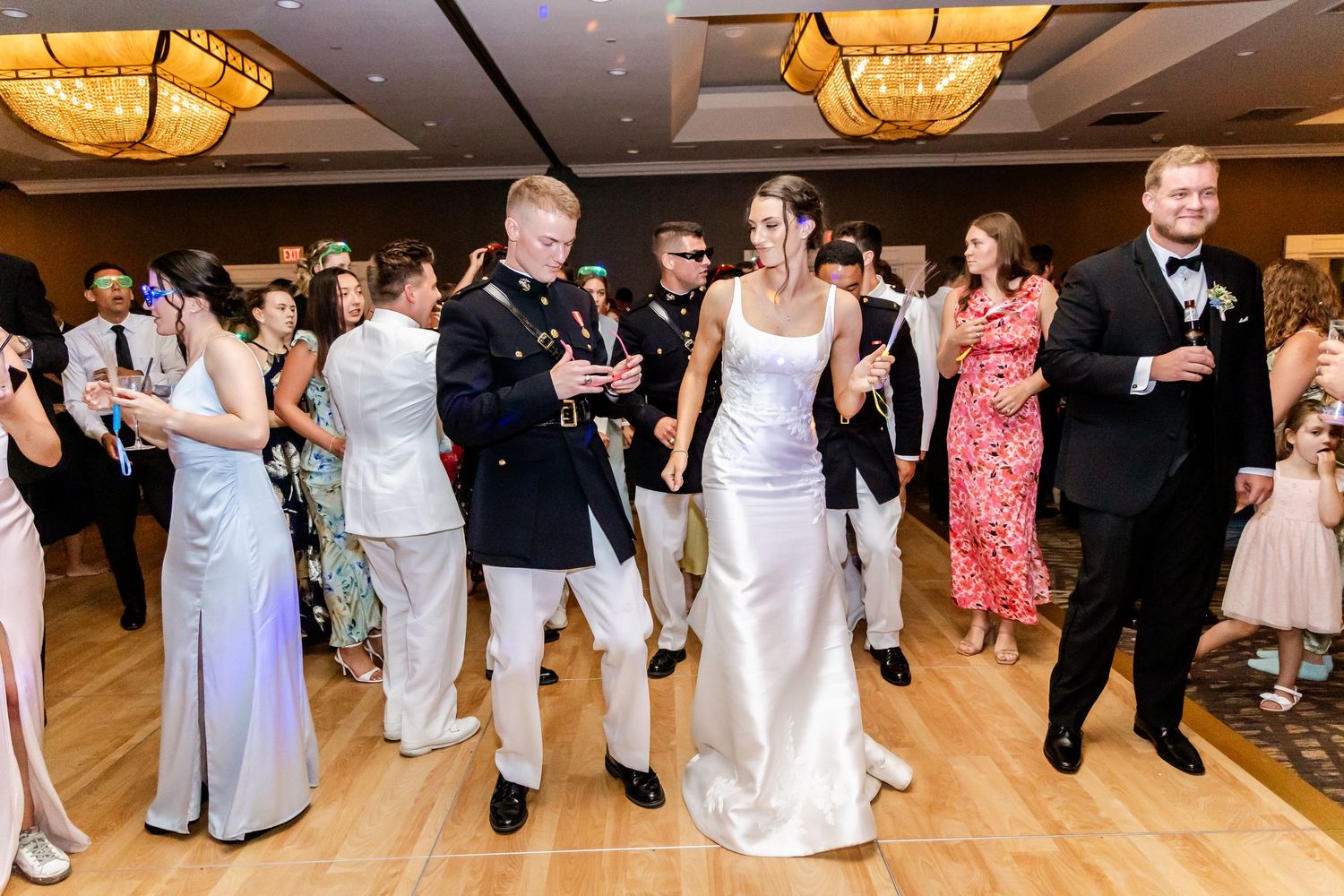 Wedding guests dancing in a line formation on a ballroom dance floor.