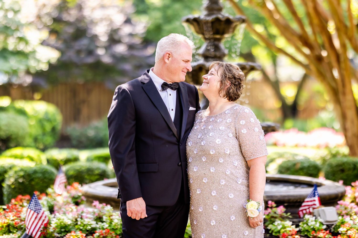 Wedding couple shares intimate moments in a lush garden setting with decorative landscaping.