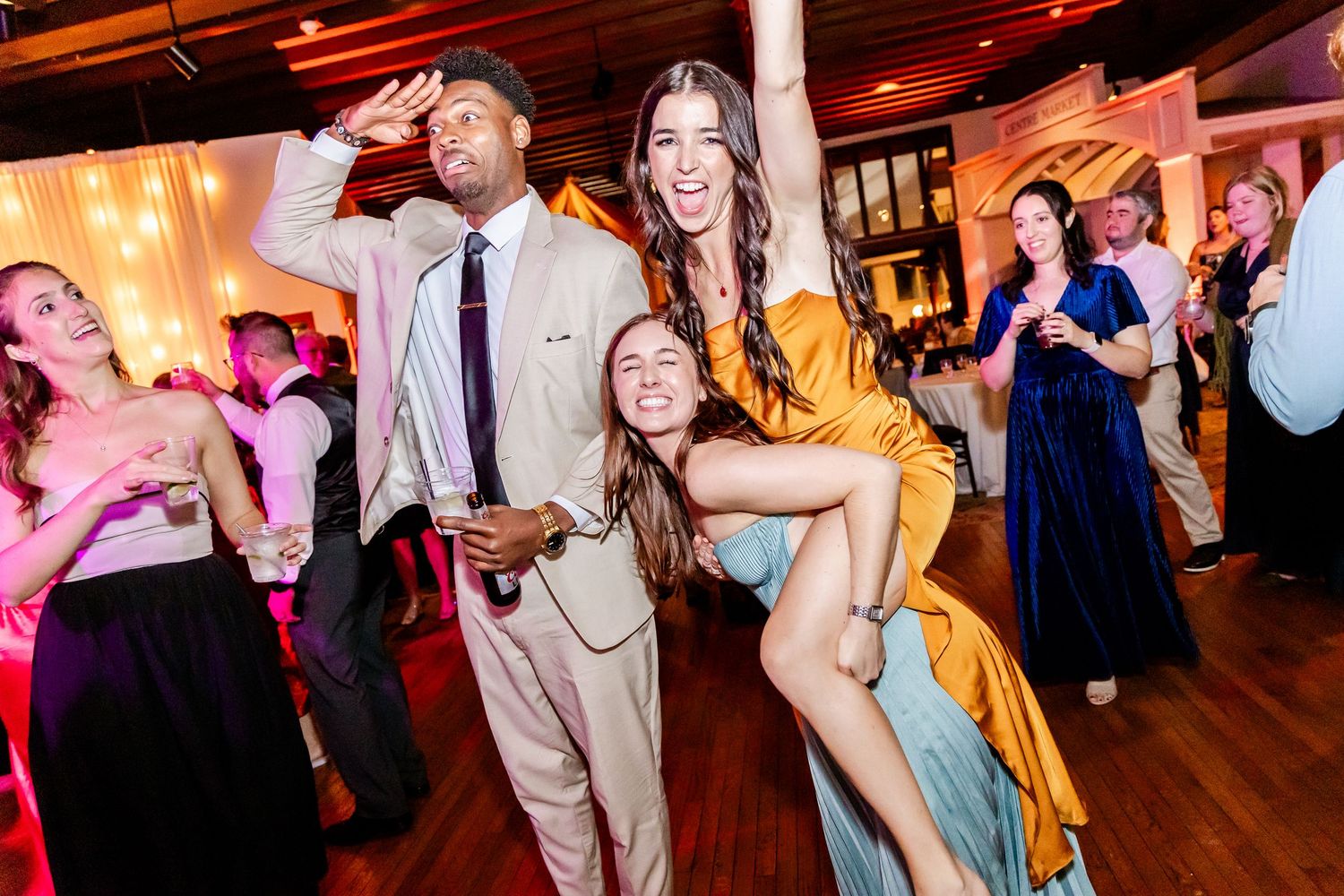 Wedding guests dance and celebrate together on a wooden dance floor at an evening reception.
