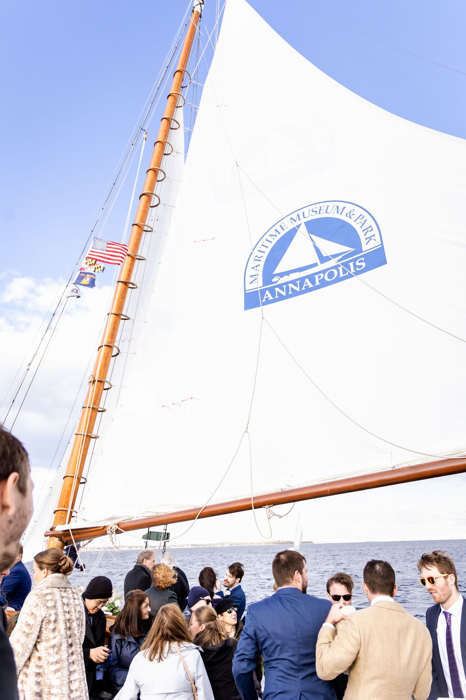 Guests gather on the deck of the Annapolis Maritime Museum & Park sailboat on a sunny day.