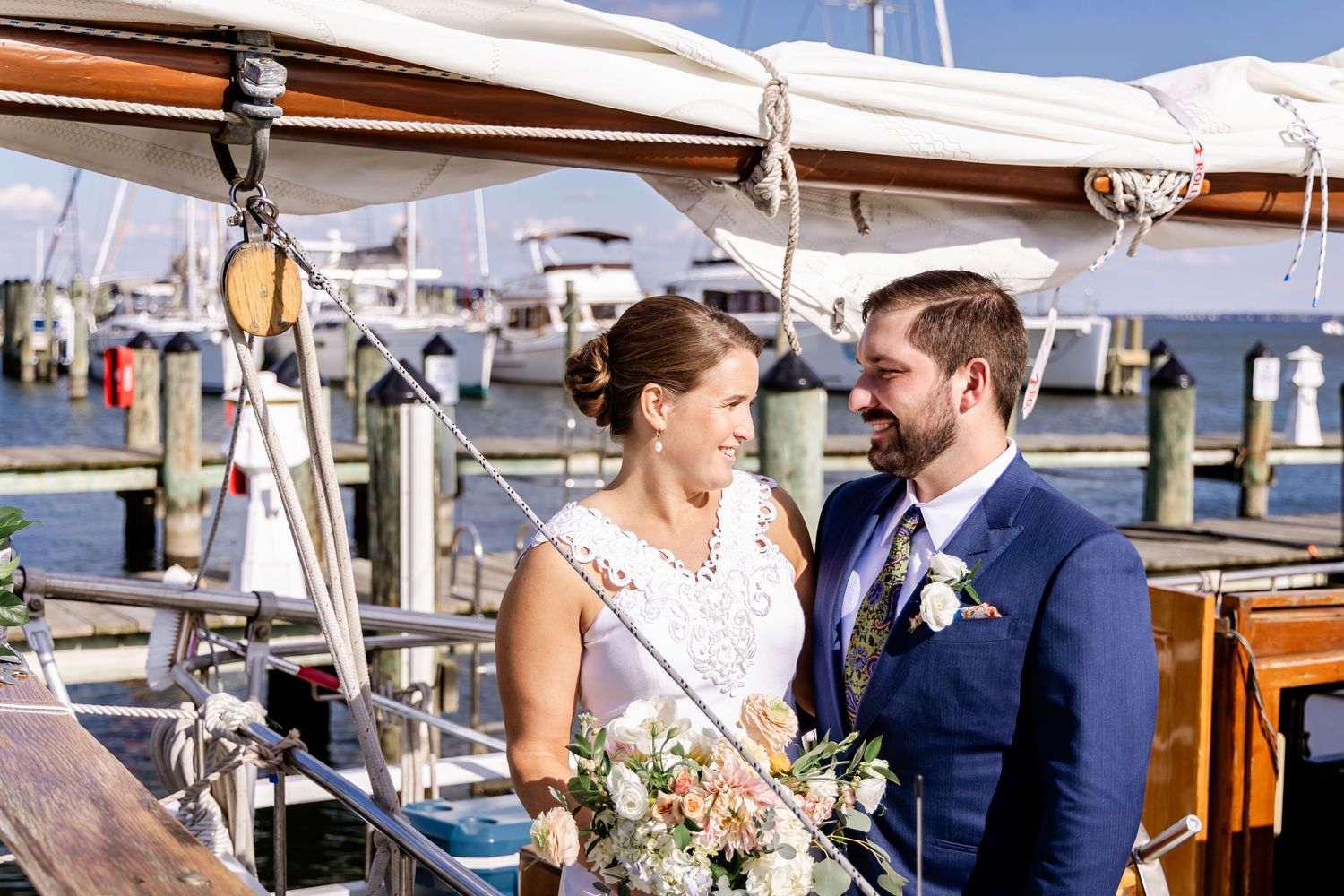 A bride and groom share a romantic moment on a sailboat at a marina on their wedding day.