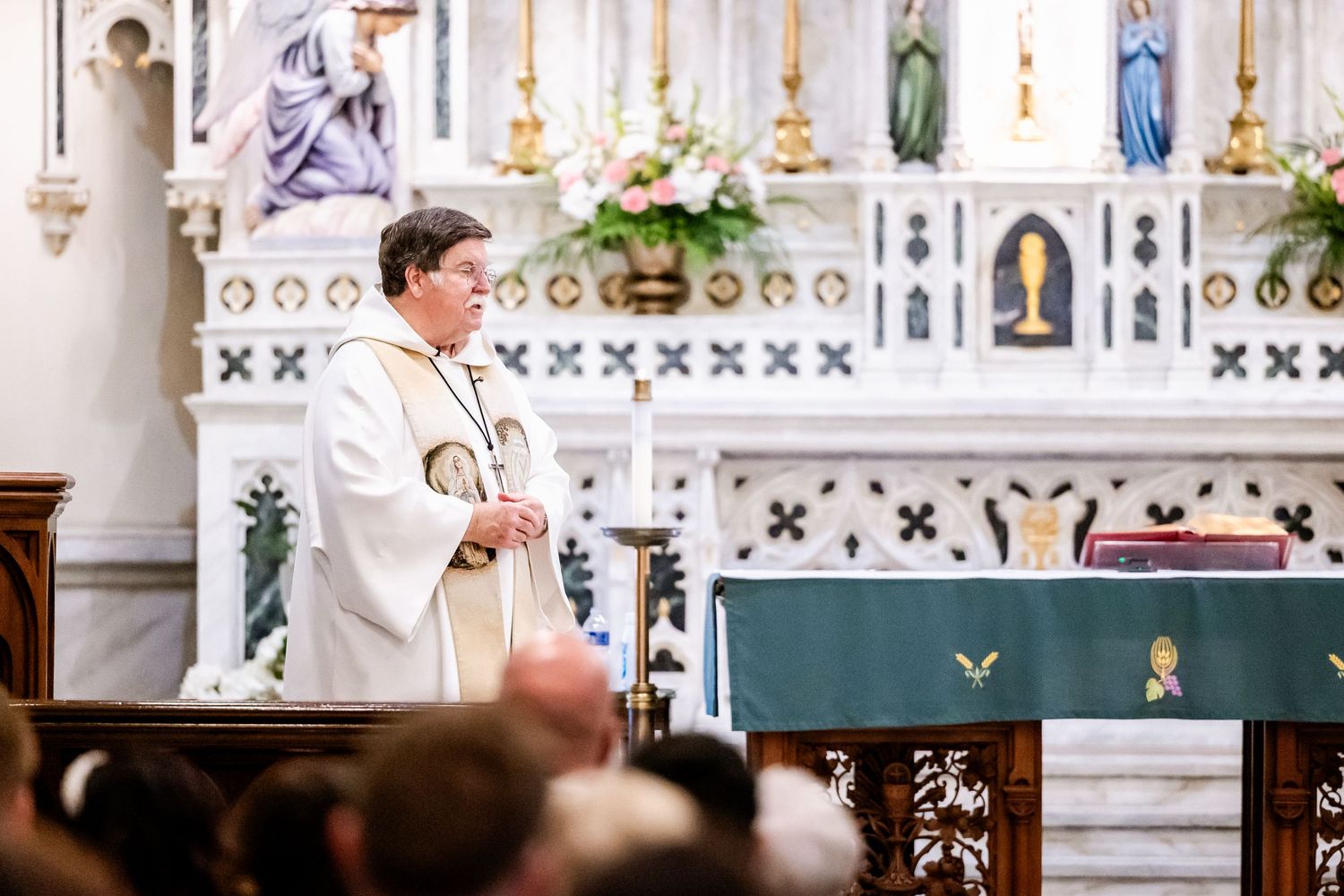 Close-up view of elaborate church altar with white Gothic details and religious statues.