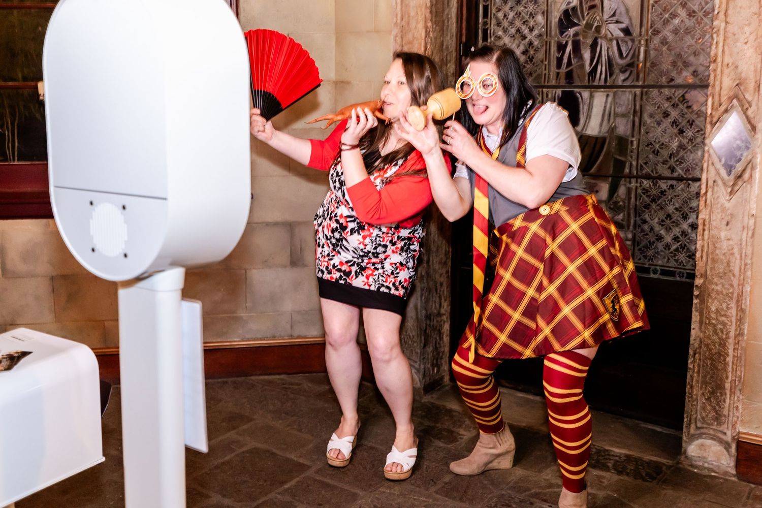 Two guests pose dramatically for a photo booth at a festive indoor party.