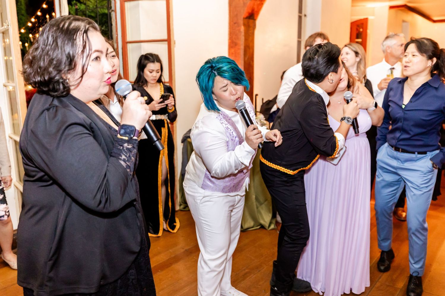 Party guests dancing and singing with joyful expressions at an indoor event.