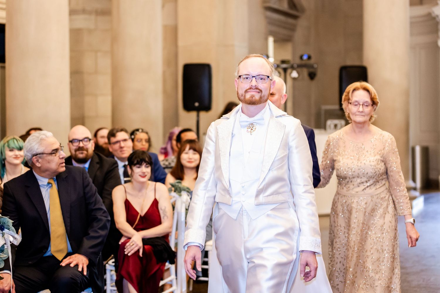 Wedding ceremony venue with elegant columns and guests seated in formal attire.