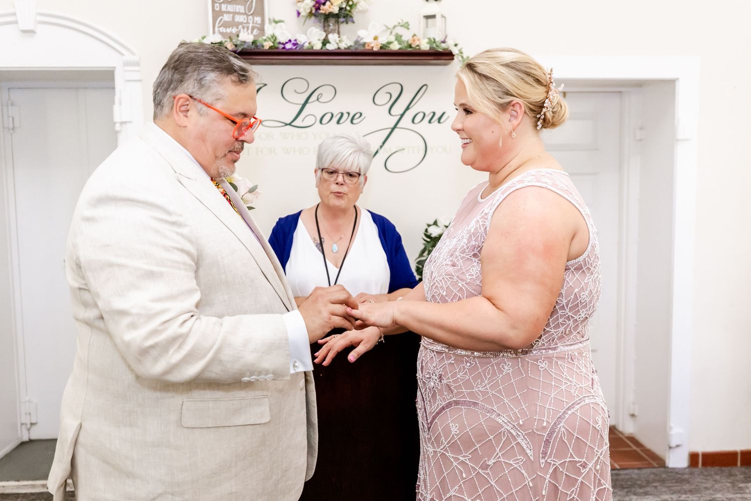 A wedding ceremony takes place under an elegant 'Love You' sign.