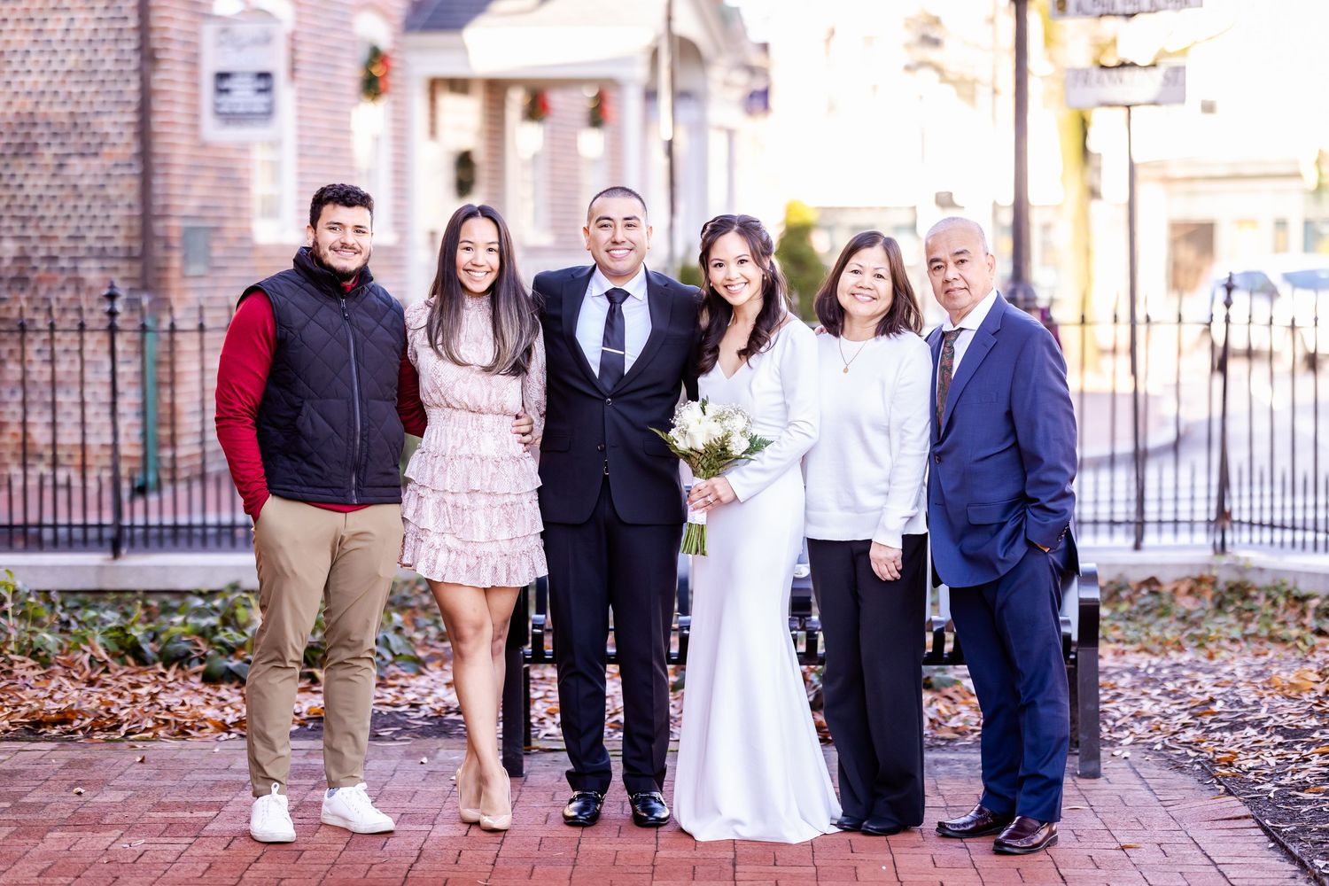 Extended family gathered for formal wedding photos on brick pathway.