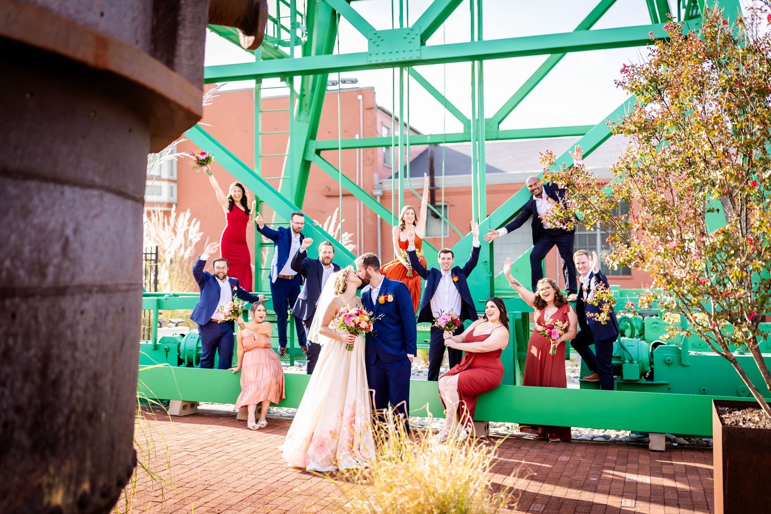 Wedding celebration beneath a bright green bridge structure with guests gathered around.