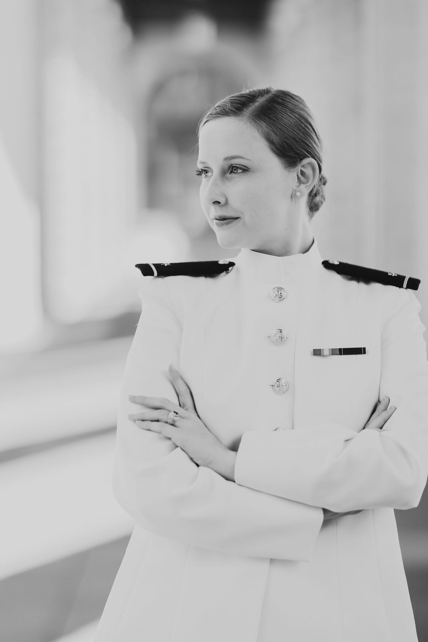 Naval officer in crisp white uniform poses confidently in black and white portrait.