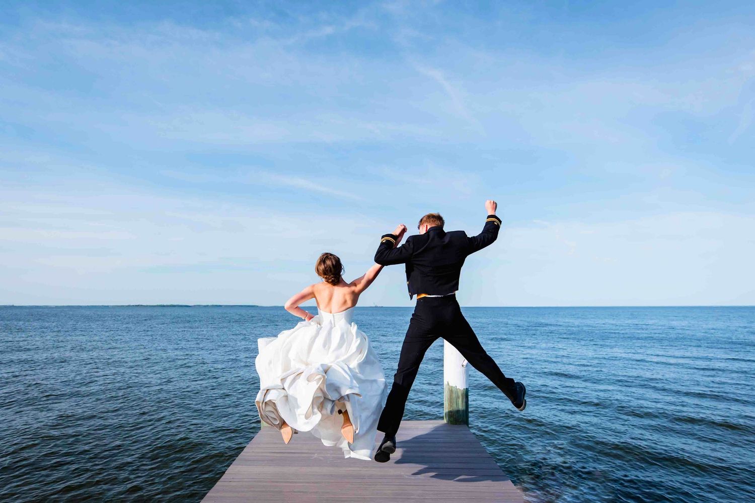 Silhouetted figures leap with joy on a beach against a bright blue ocean and sky backdrop.