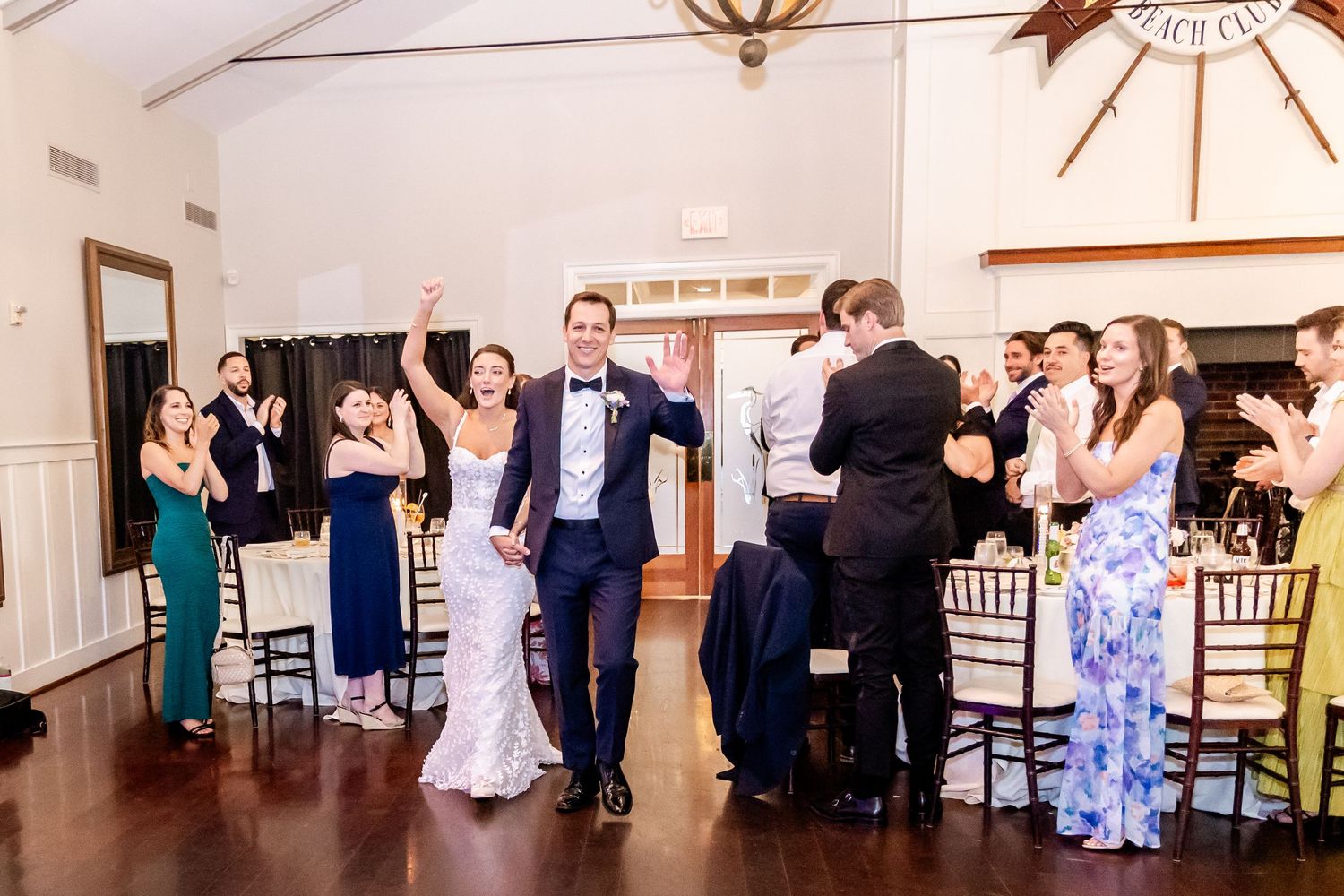 Wedding guests celebrate with the newlyweds during their reception in an elegant white room.