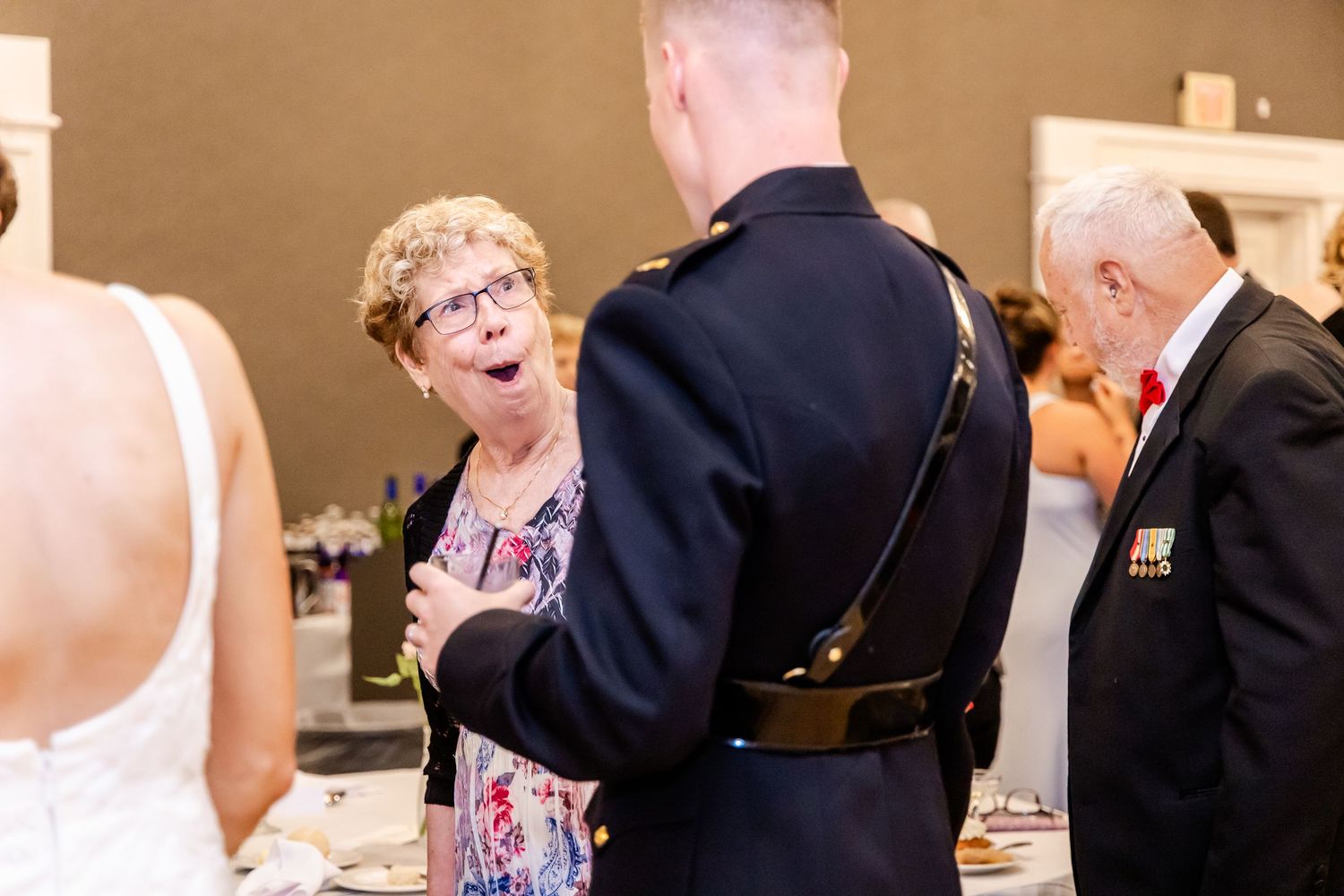 Wedding guests gather and interact during an indoor reception celebration.