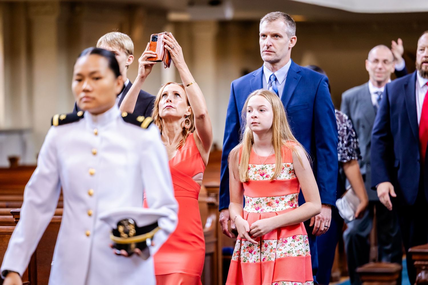Wedding ceremony guests mingle in formal attire at an elegant church venue.