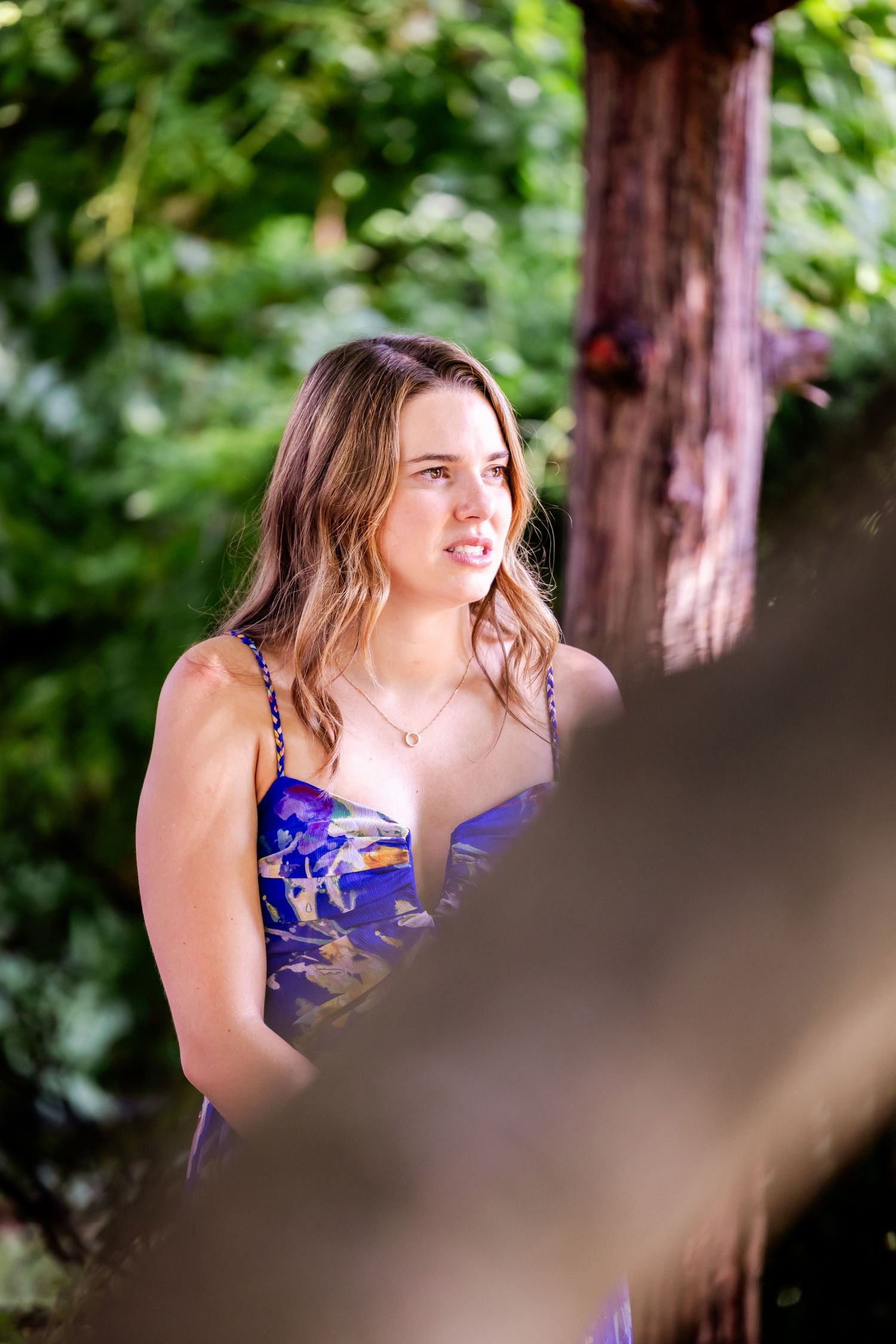 Person in purple dress smiles during outdoor wedding ceremony.