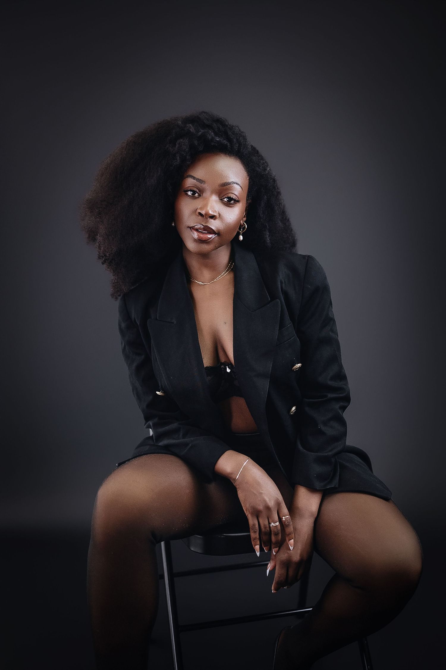 Artistic portrait in dark lighting featuring a black blazer against moody background.