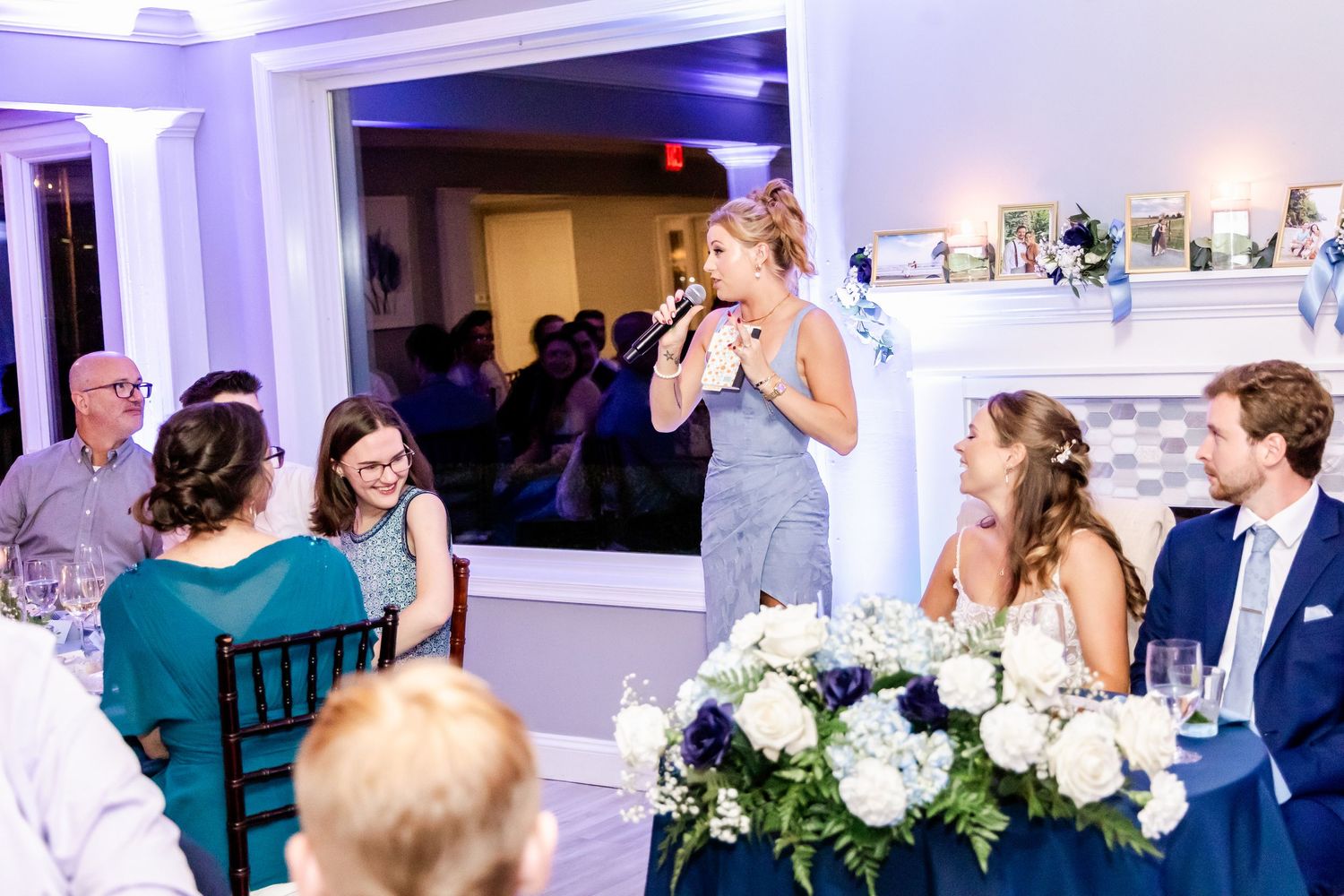 Elegant wedding reception venue decorated with white floral arrangements and soft purple lighting.