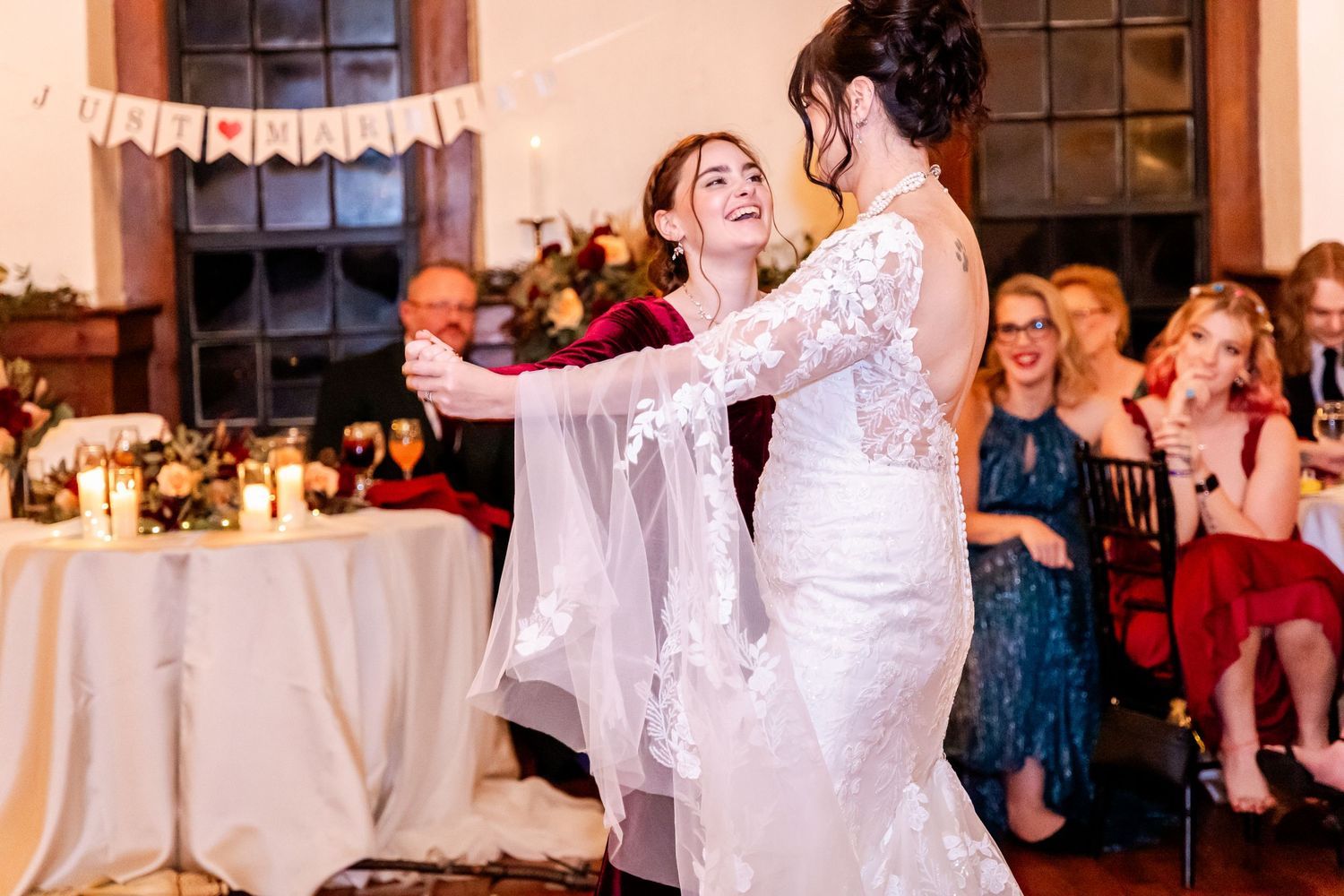 Wedding guests dancing and celebrating together at a reception with string lights and decorations.