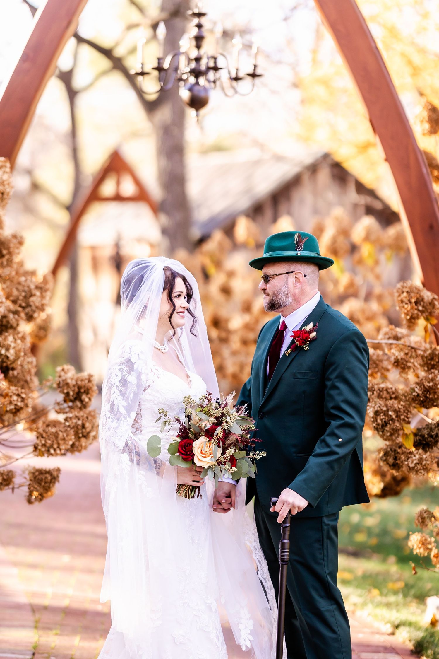 A couple poses together in a romantic outdoor autumn setting with golden foliage.