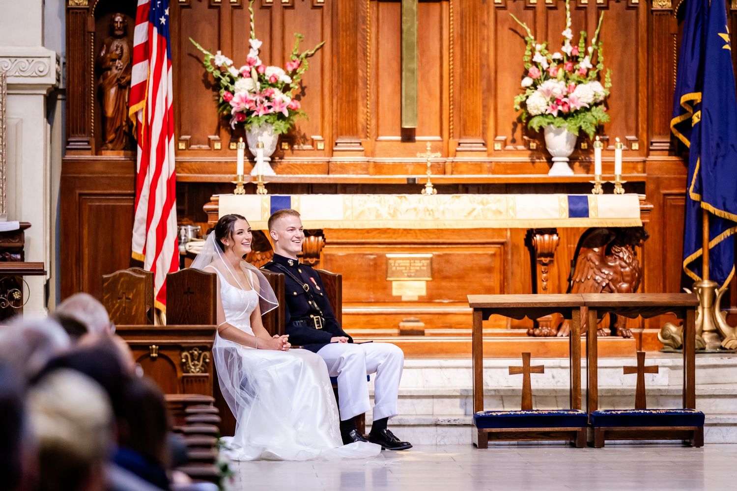 Traditional church wedding ceremony with American flags and floral arrangements at the altar.