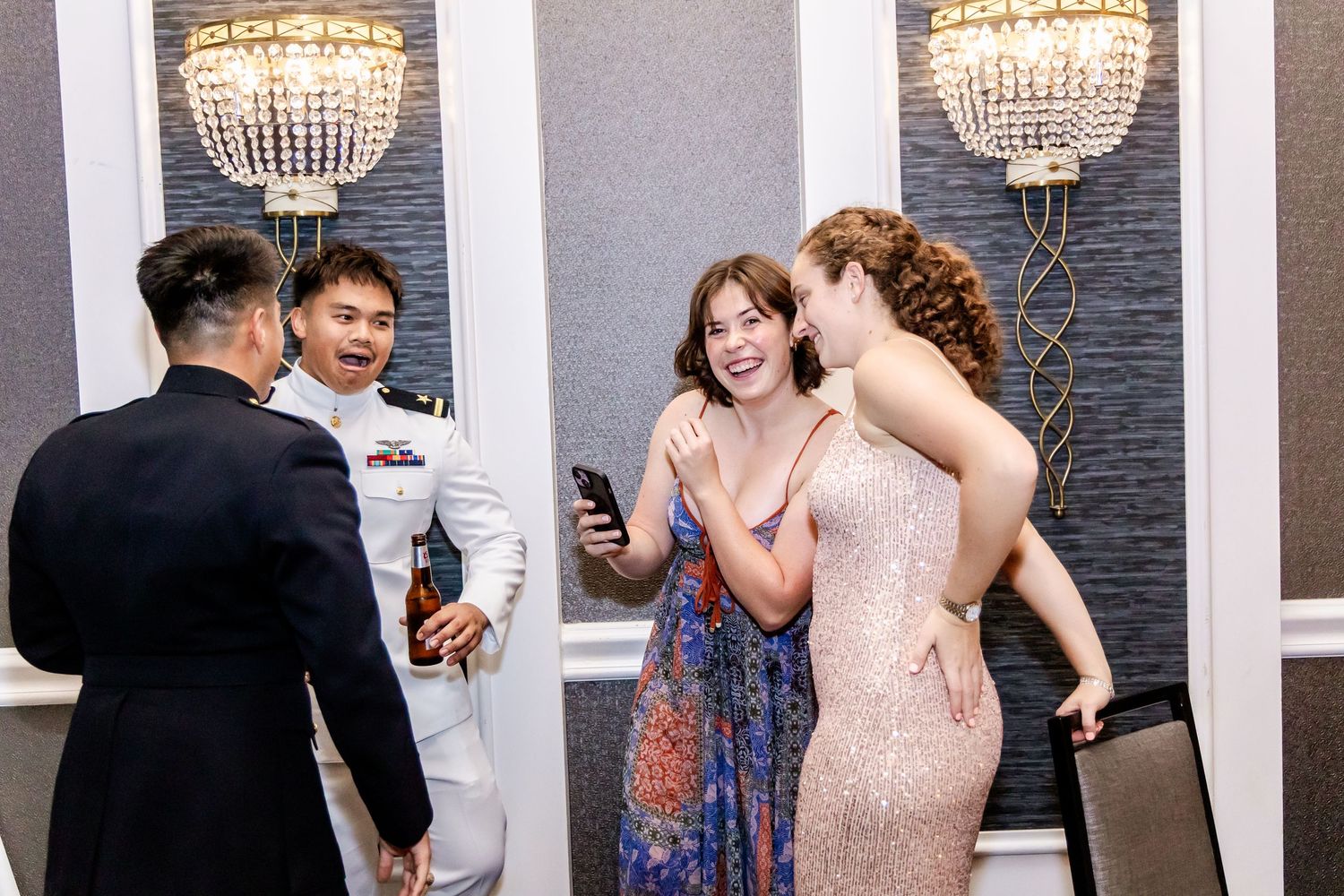 Crystal chandeliers illuminate an elegant reception venue with guests dancing.