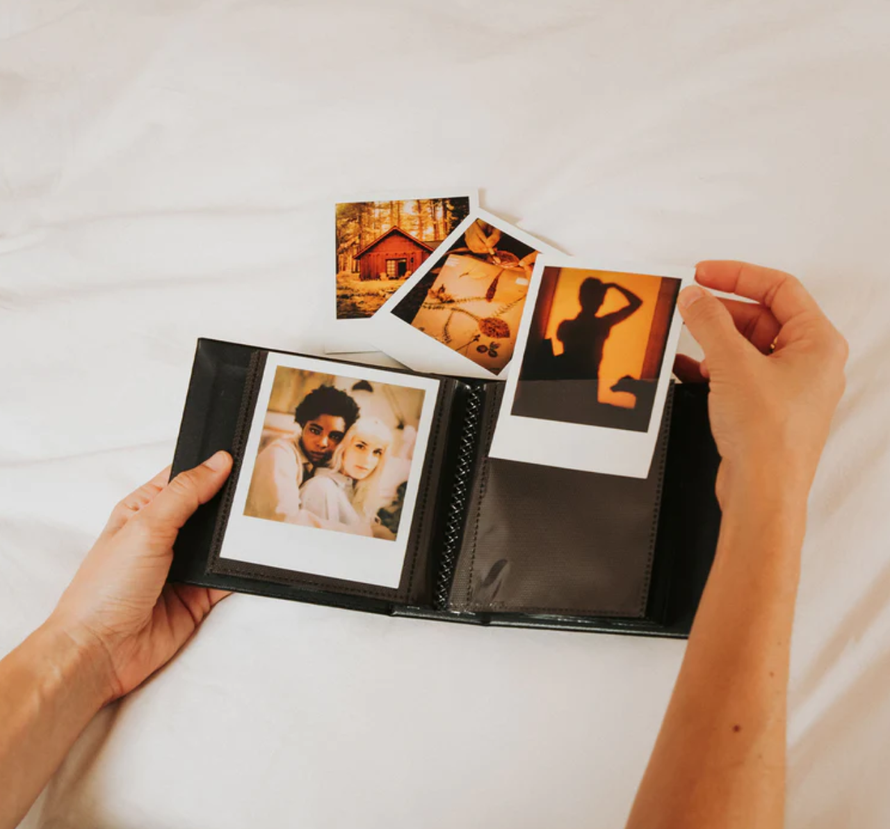 Hands flipping through a wedding photo album showing printed photographs and memories.