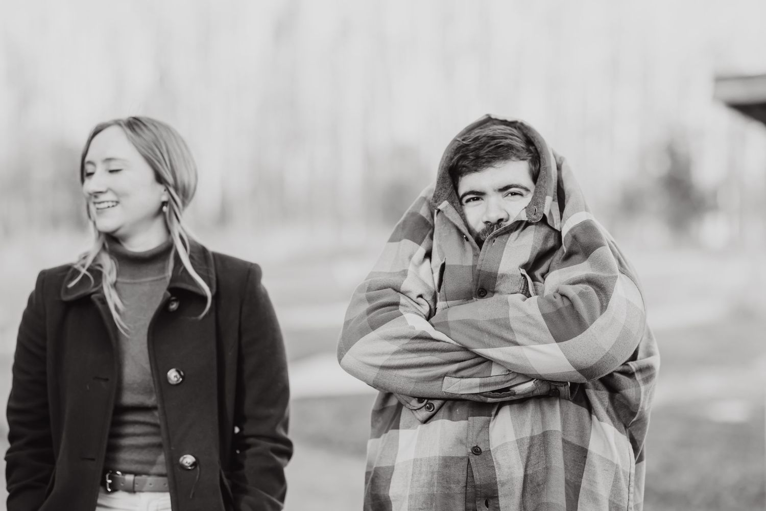 Two people laughing together outdoors in black and white photography.
