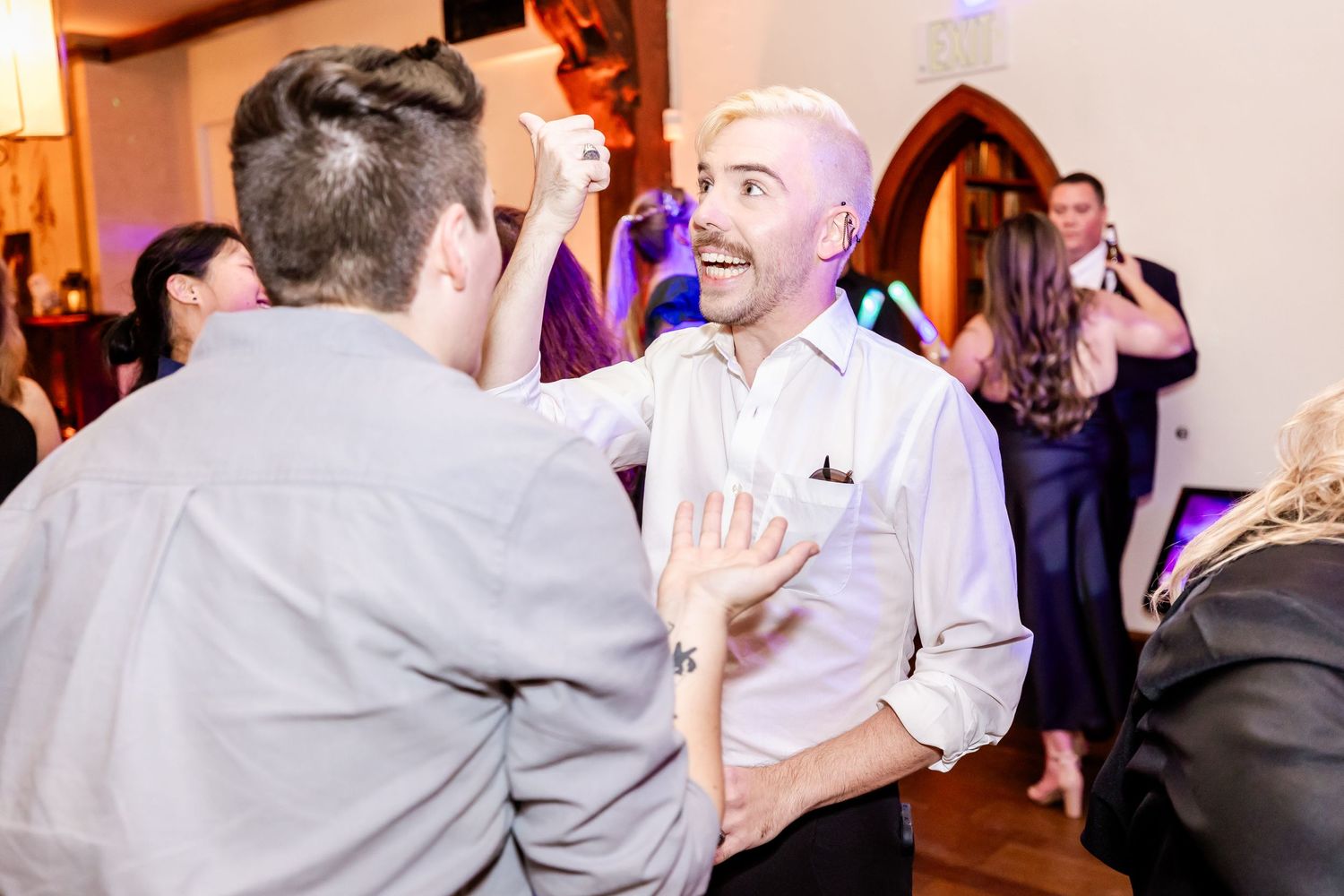 Two partygoers share an enthusiastic greeting while dancing at an indoor celebration.