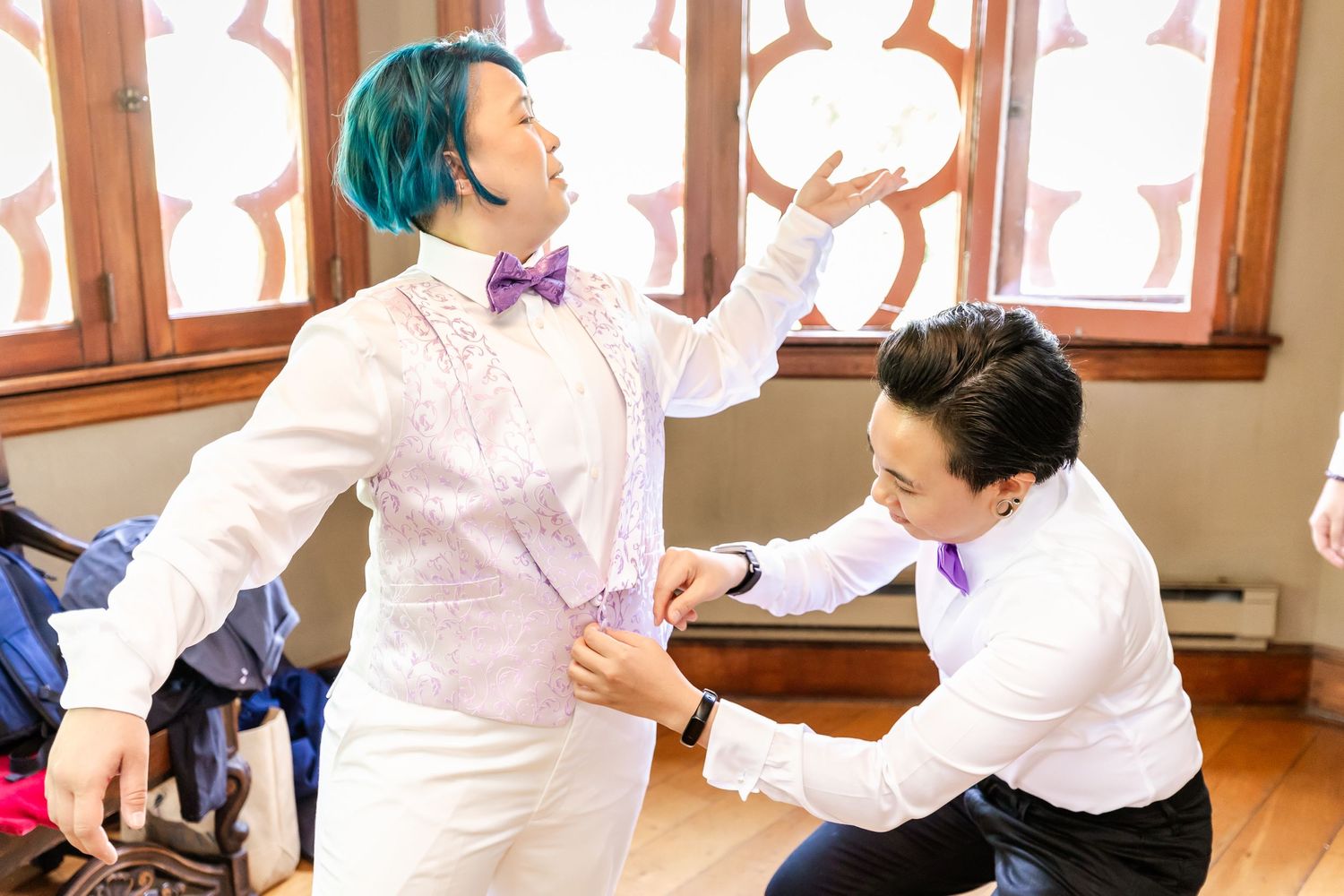 Wedding preparation moment captured indoors with gothic window details.