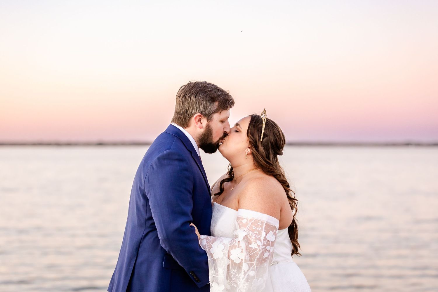 A tender wedding moment captured during sunset on a waterfront dock.