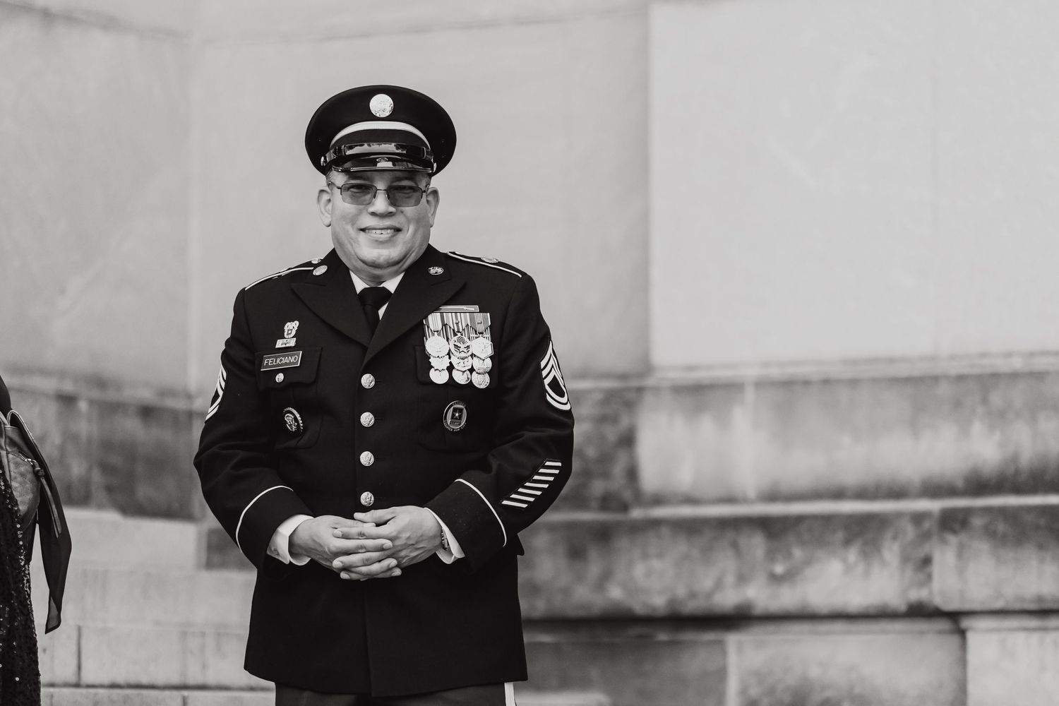 Black and white portrait of uniformed officer standing at attention during wedding ceremony.
