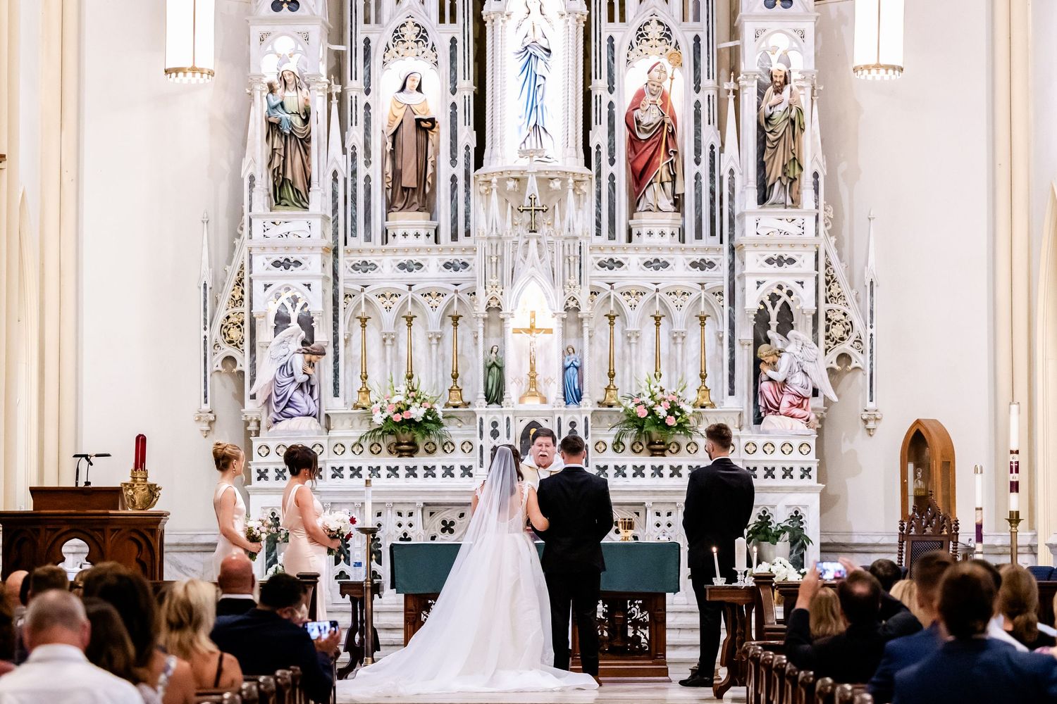 Elegant church wedding ceremony in a grand cathedral with white marble altar and stained glass windows.