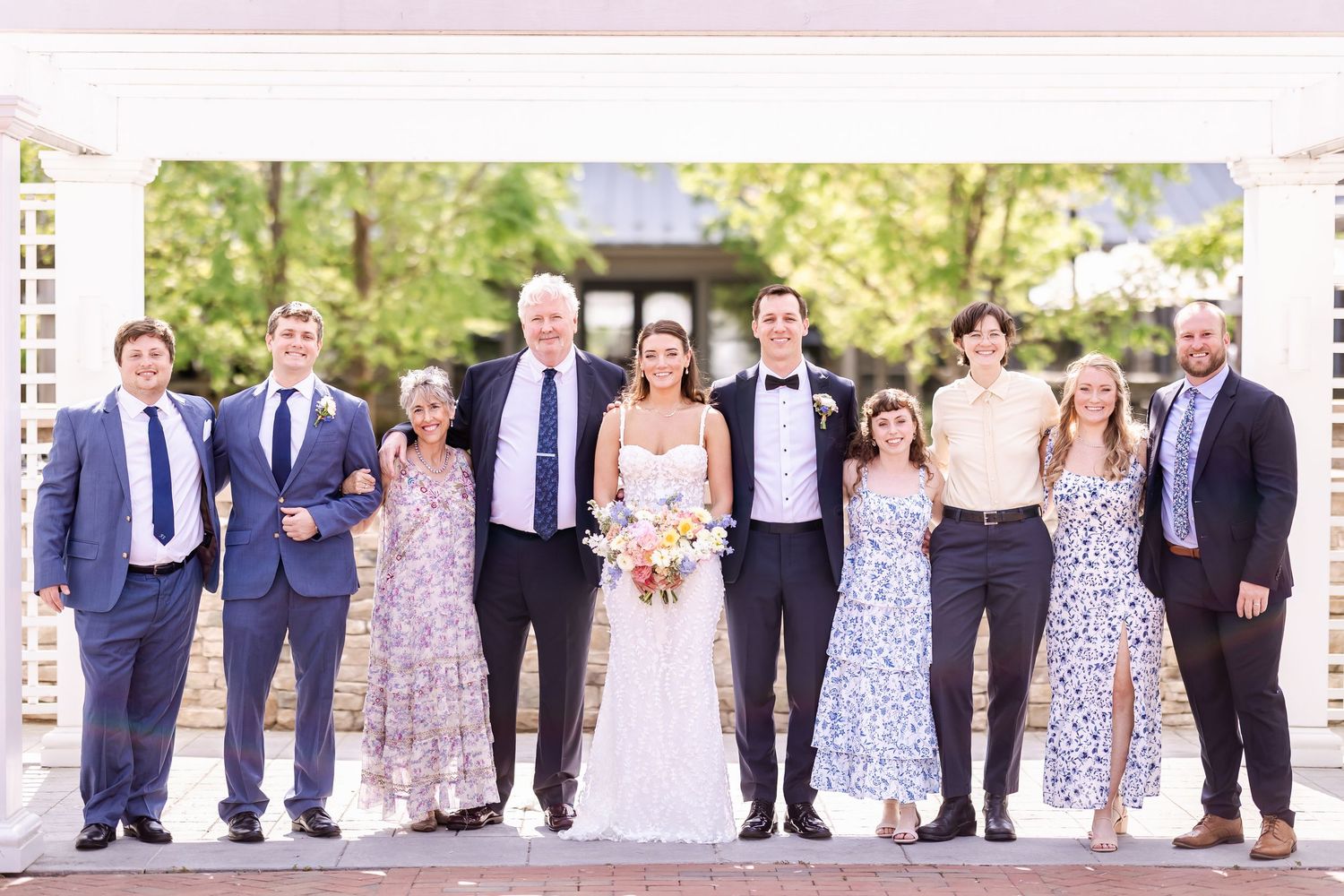 Large wedding party group photo with attendants in blue and floral attire.