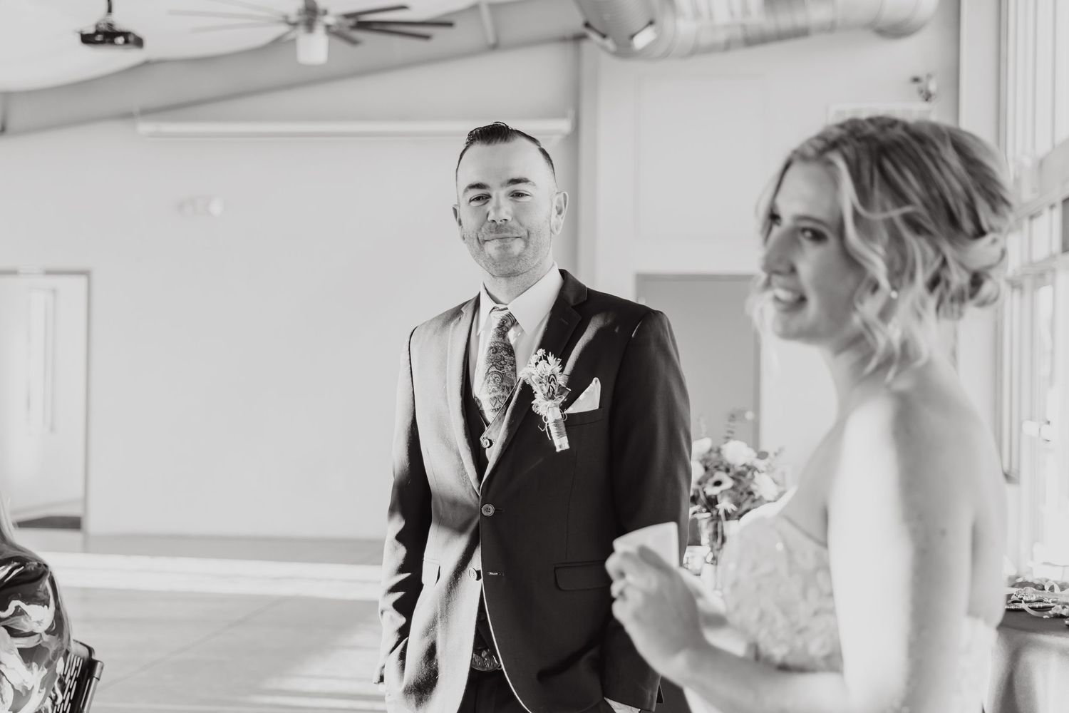 A black and white photo captures a joyful wedding moment with the happy couple sharing a candid interaction.