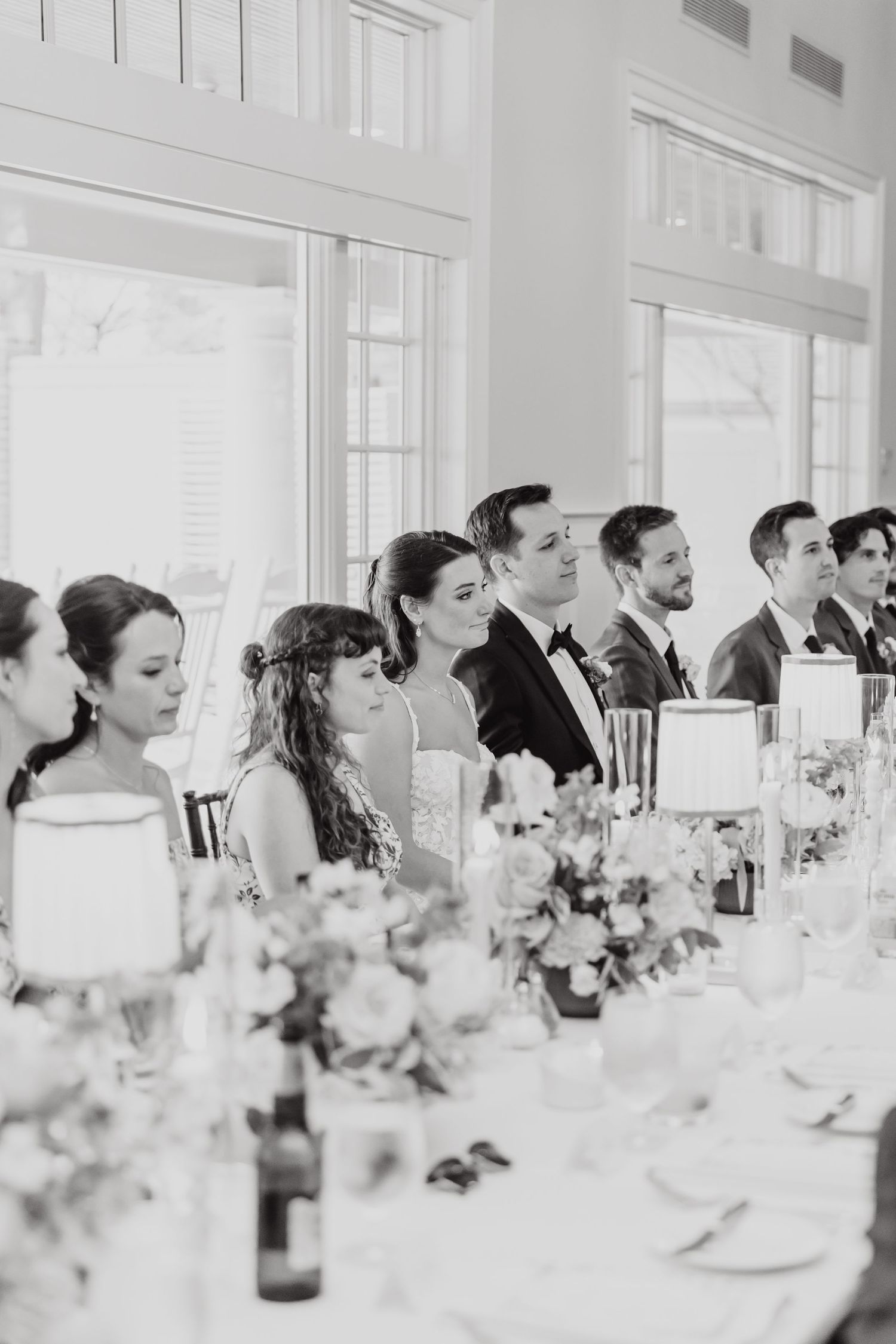 Wedding reception table settings with floral centerpieces in an elegant white room.