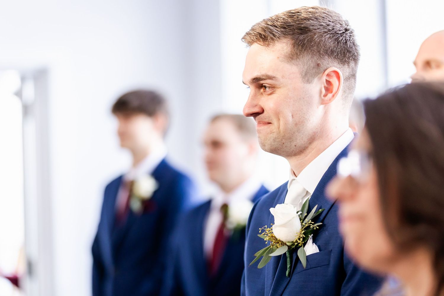 Wedding guests in formal attire mingle during an elegant indoor reception celebration.