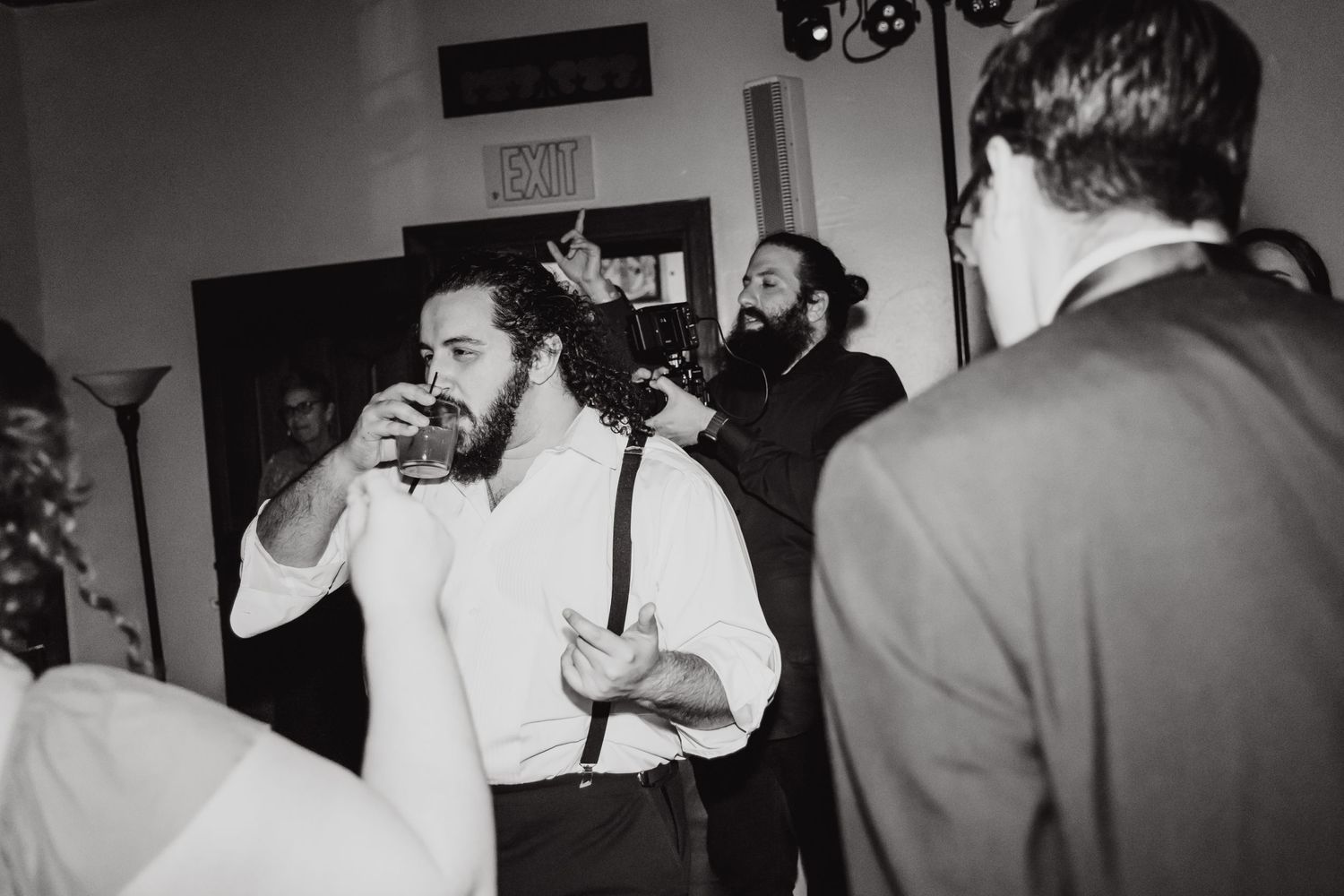Black and white photo of guests enjoying drinks and socializing at an indoor celebration.