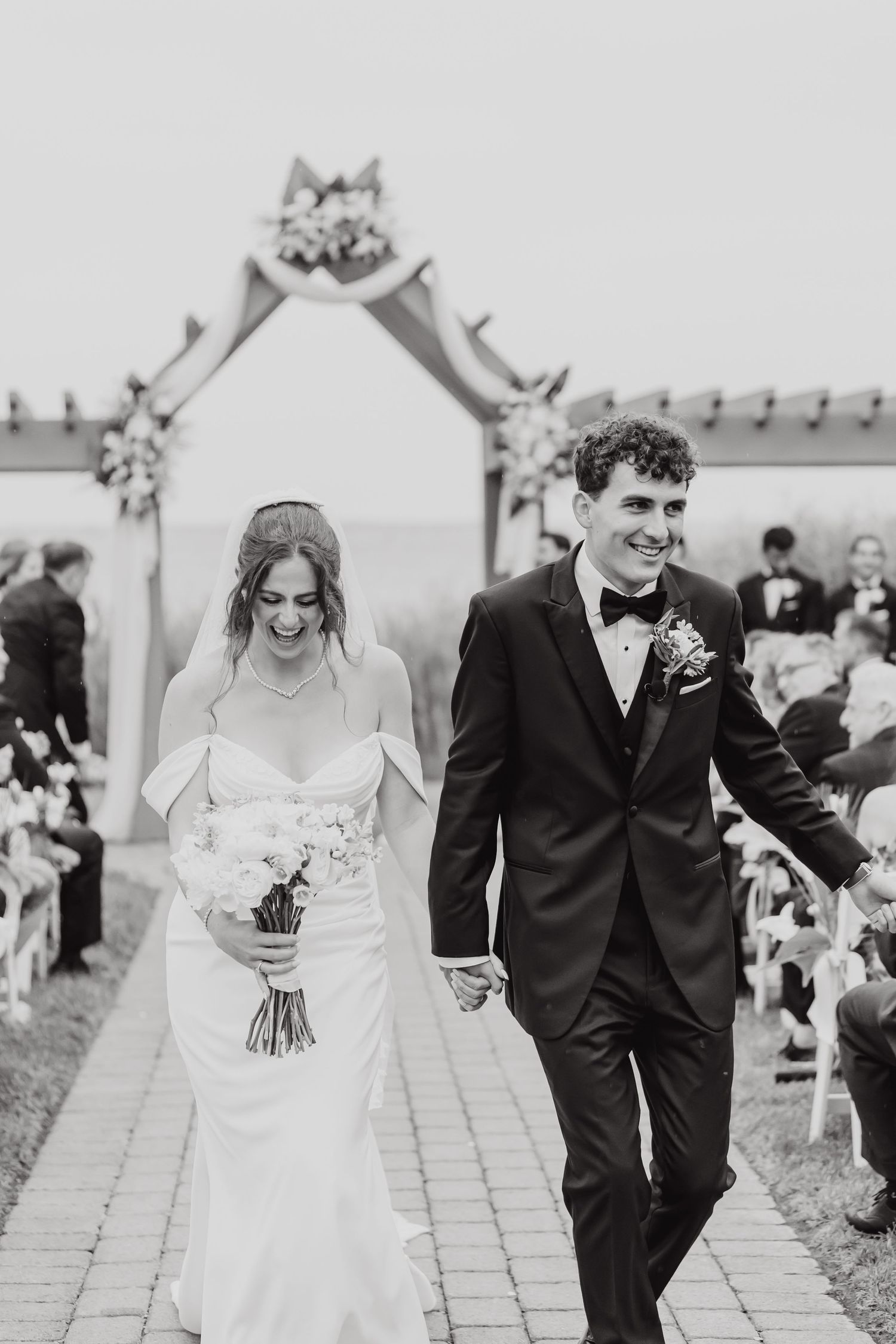 Newlyweds walking together along a stone path during their outdoor wedding ceremony.