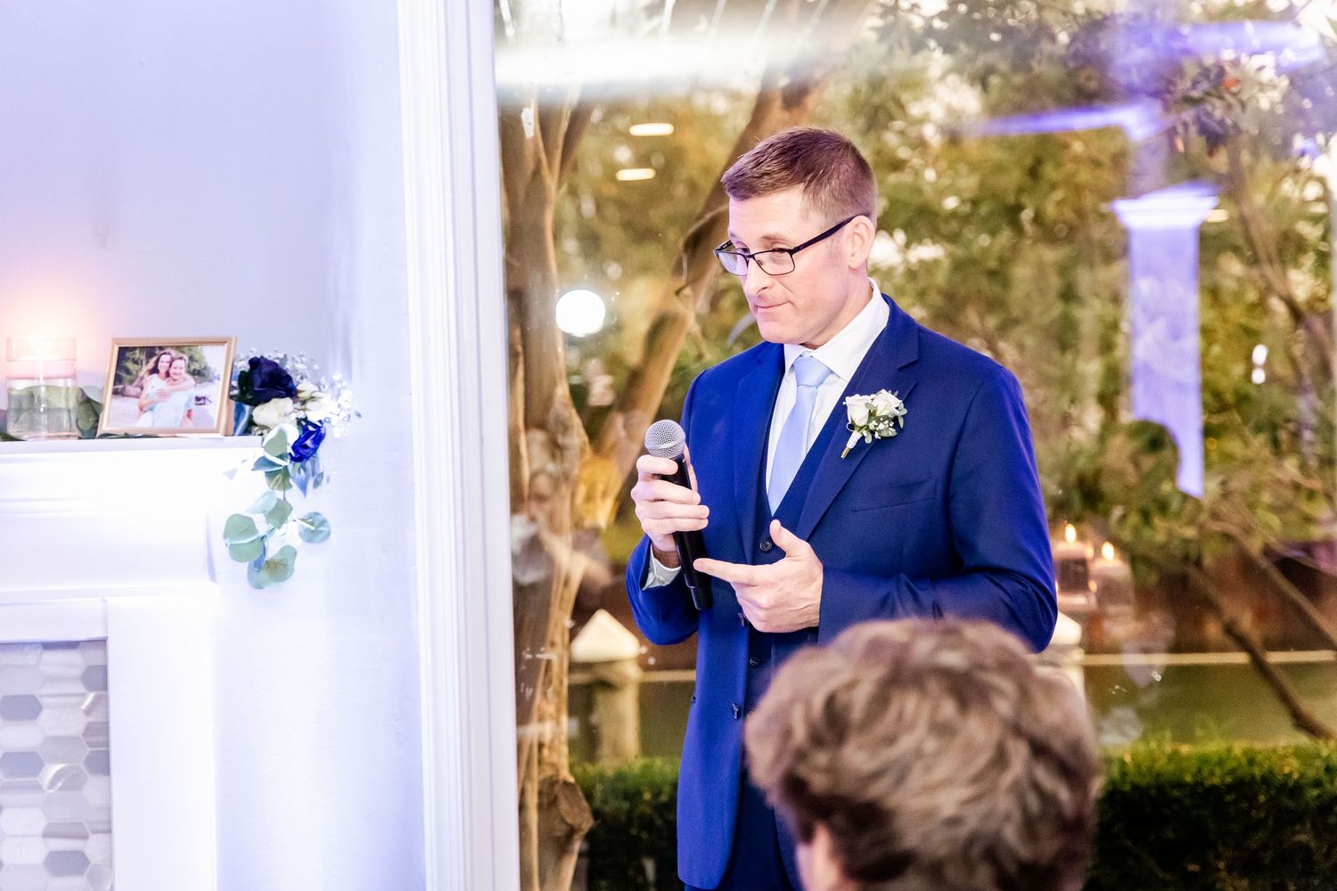 Wedding reception venue with draped ceiling and outdoor garden views through large windows.