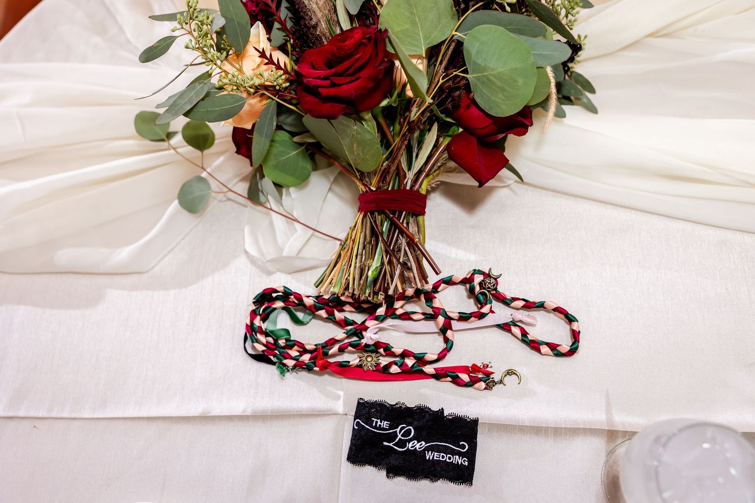 Close-up of burgundy and white floral wedding table decorations with greenery.