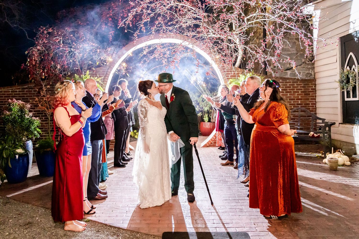Wedding party exit through sparkler tunnel with guests creating magical nighttime atmosphere.