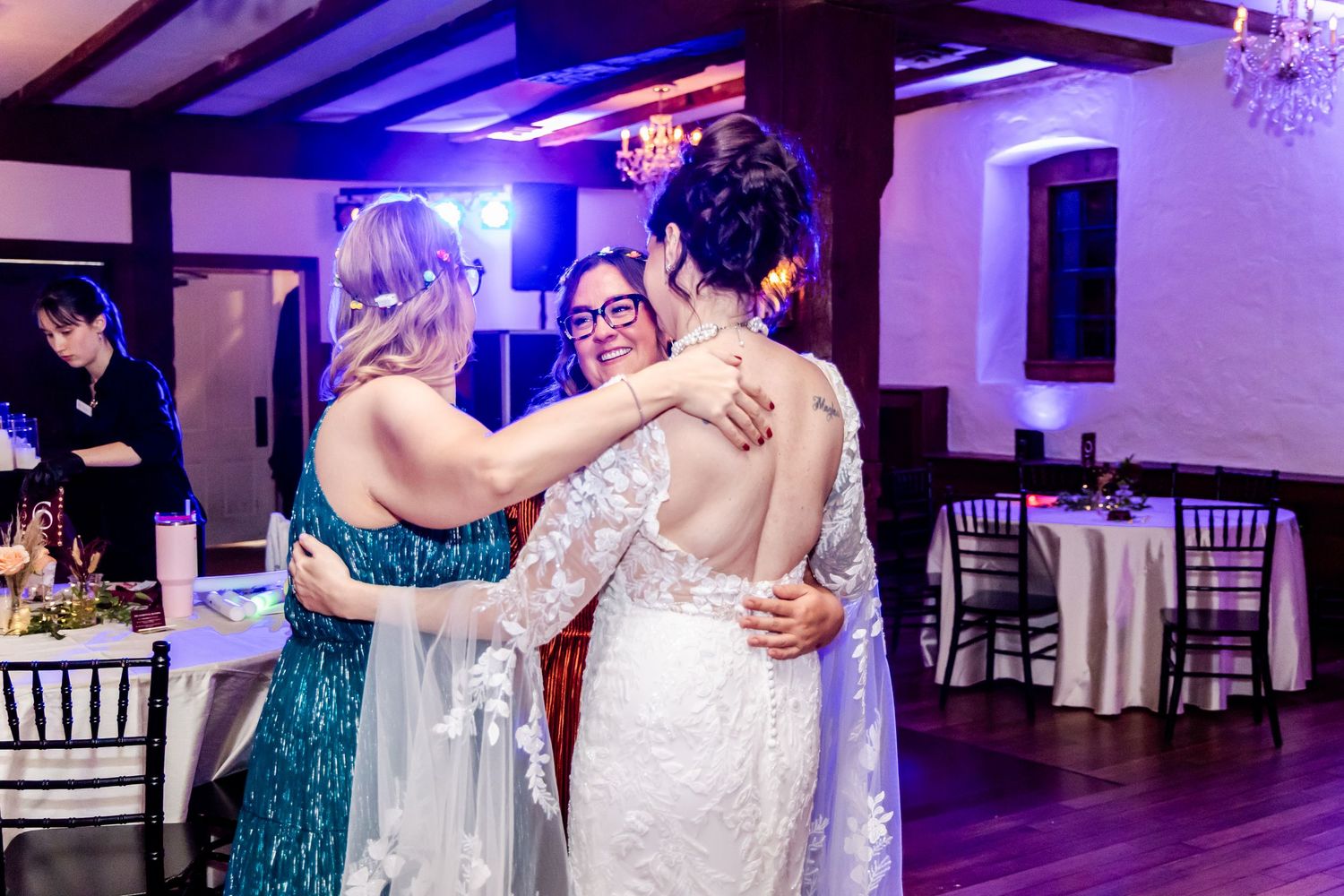 Wedding reception dance floor with purple mood lighting and guests celebrating in an elegant venue.