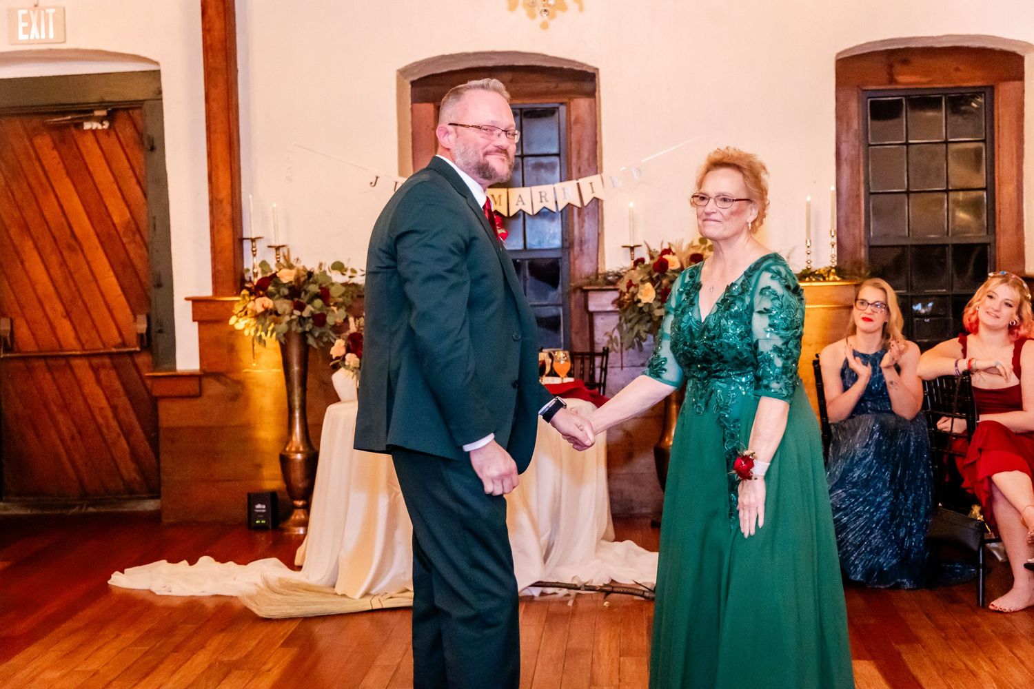 Wedding reception guests dancing and celebrating on a wooden dance floor.