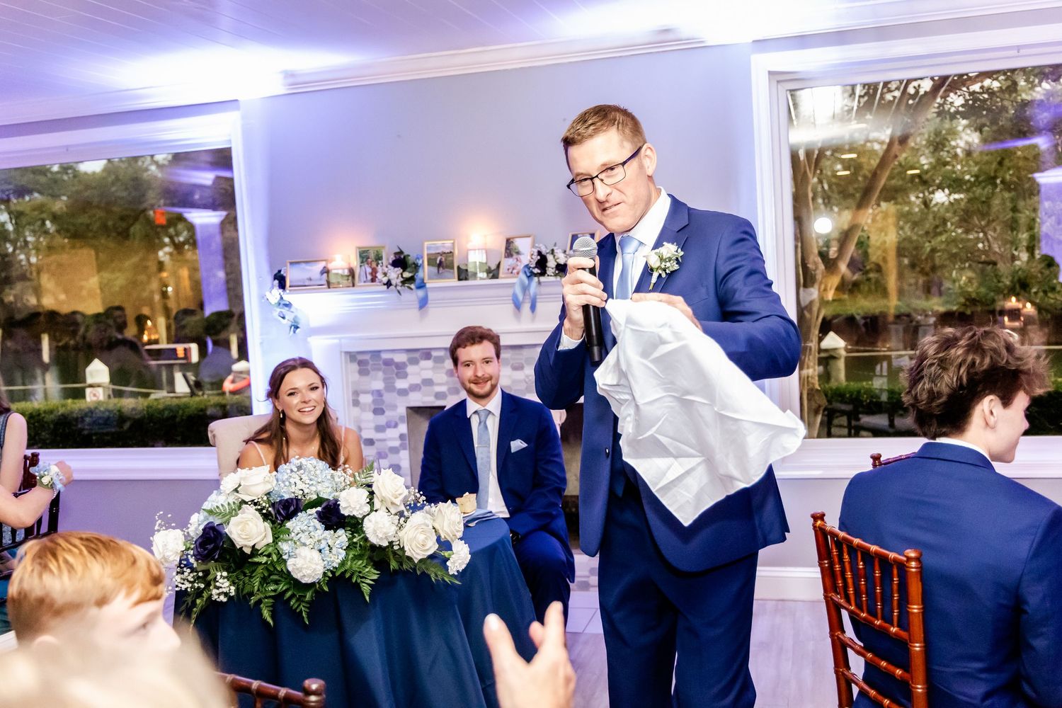 Wedding reception venue decorated with blue lighting and white draping.