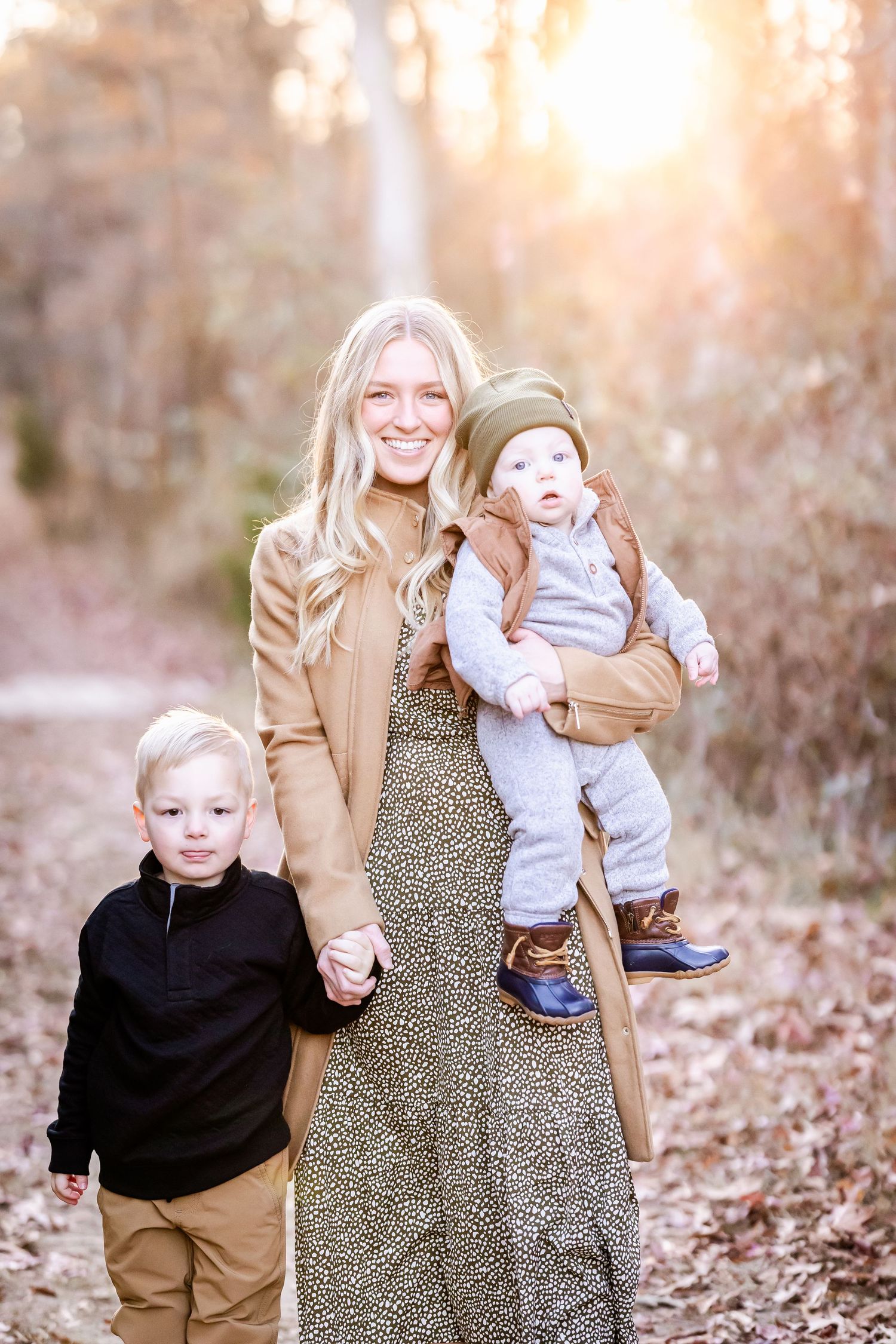 Family enjoying an autumn walk together on a leaf-covered path in warm coordinating outfits during golden hour.