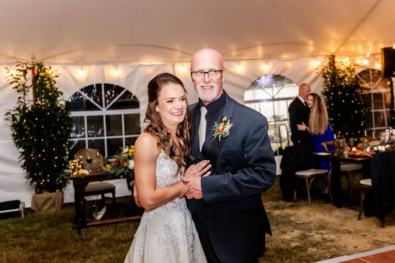 Couples dance together under string lights at evening wedding reception.