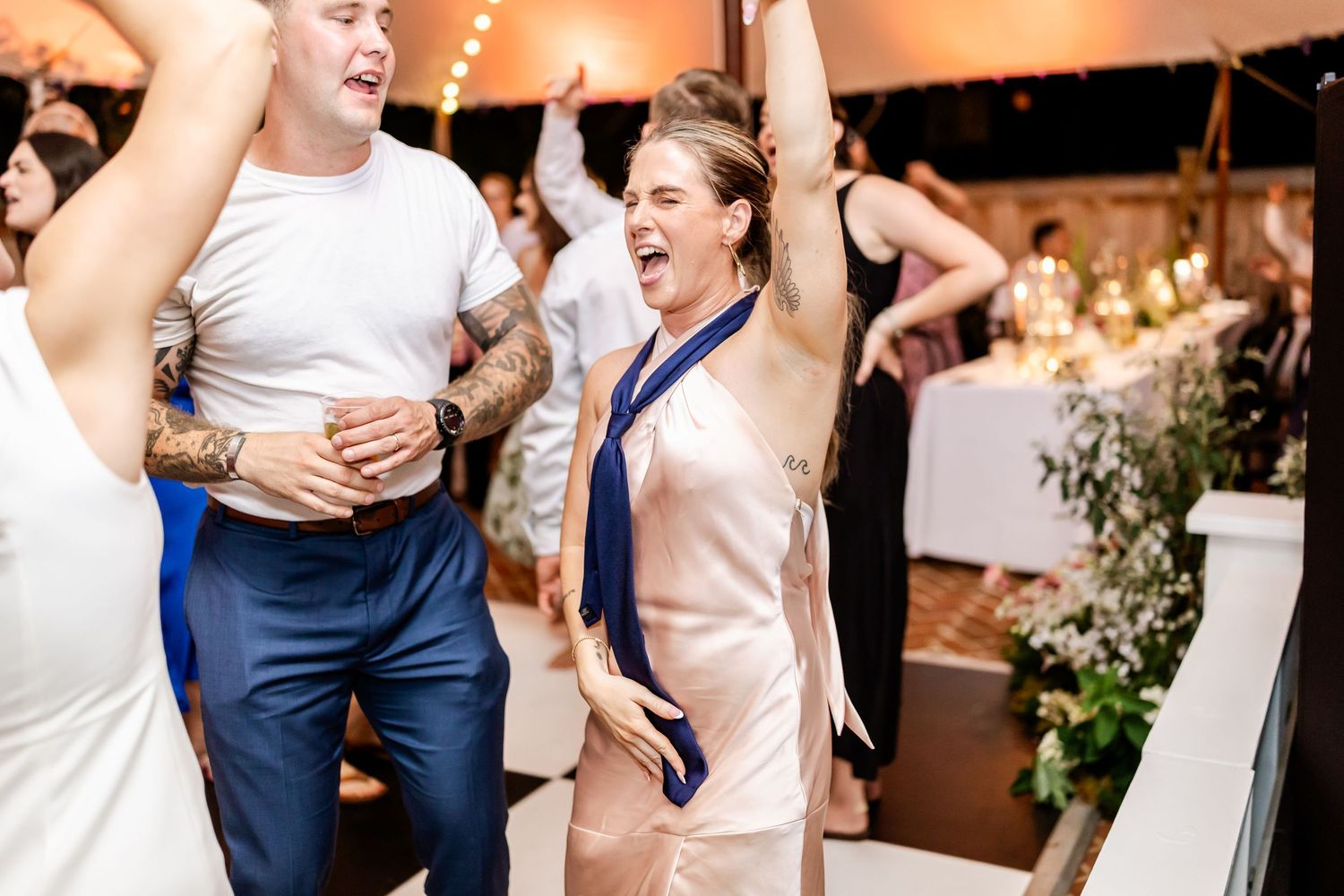 Joyful wedding party dancing and celebrating during an indoor reception.